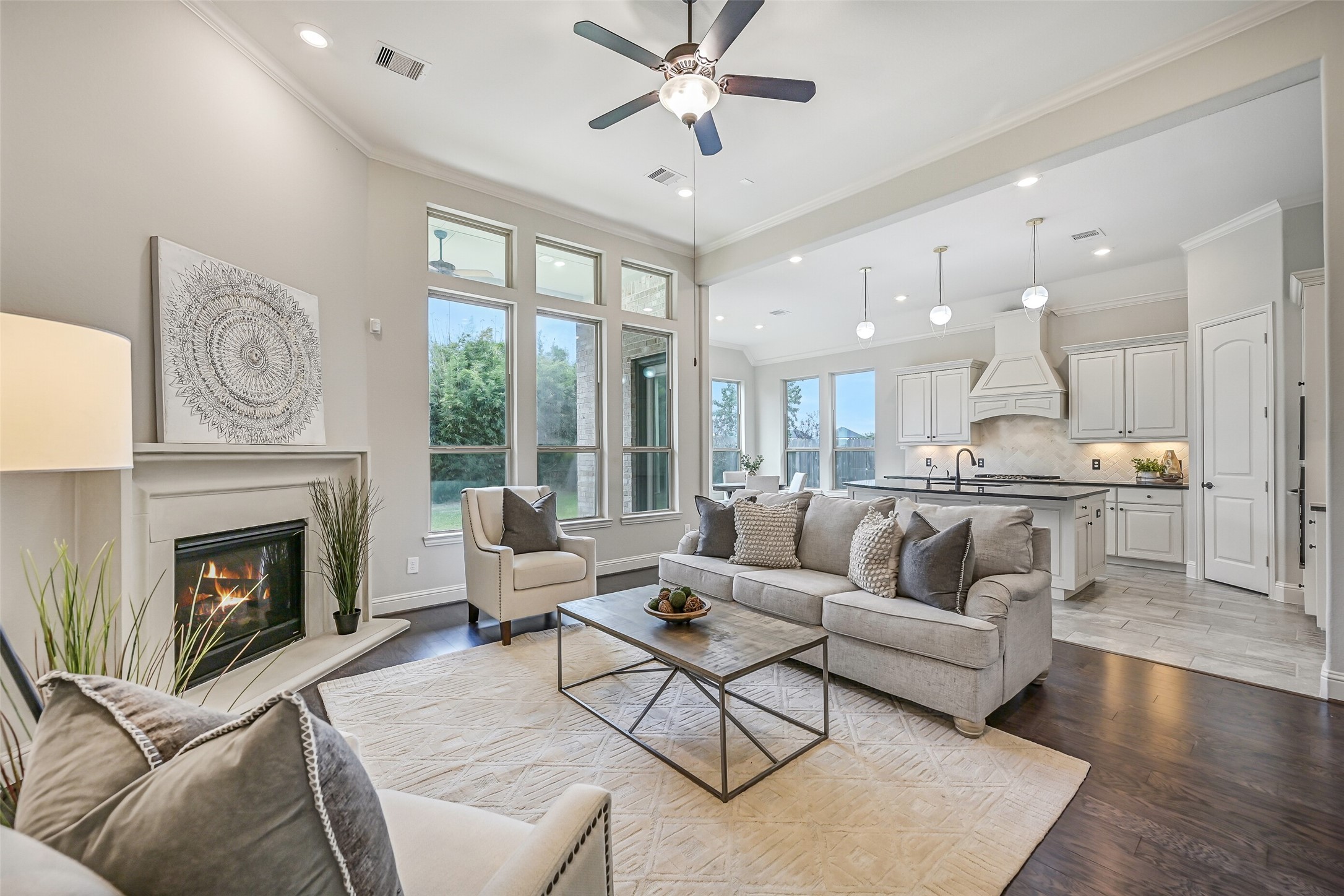 Come on in! Soaring ceilings, rich luxury vinyl plank flooring & a cast-stone gas-log fireplace welcome you into the spacious family room. A wall of windows brings in natural light, while the open design connects seamlessly to the kitchen & breakfast room.