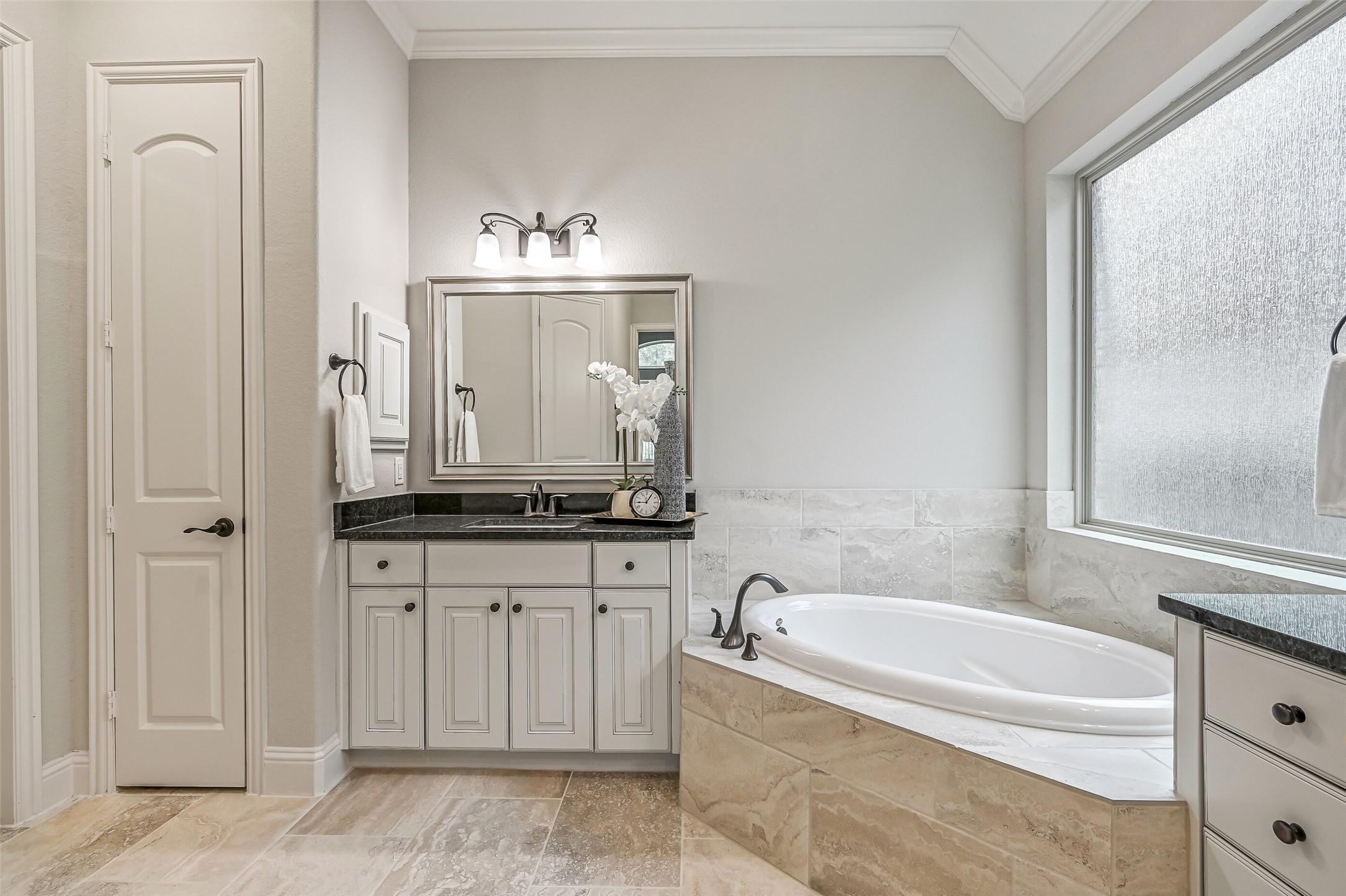 Another look at the primary bath highlights the second granite-topped vanity, framed mirror & inviting soaking tub with its tiled surround. A generous walk-in closet provides plenty of room for wardrobe storage.
