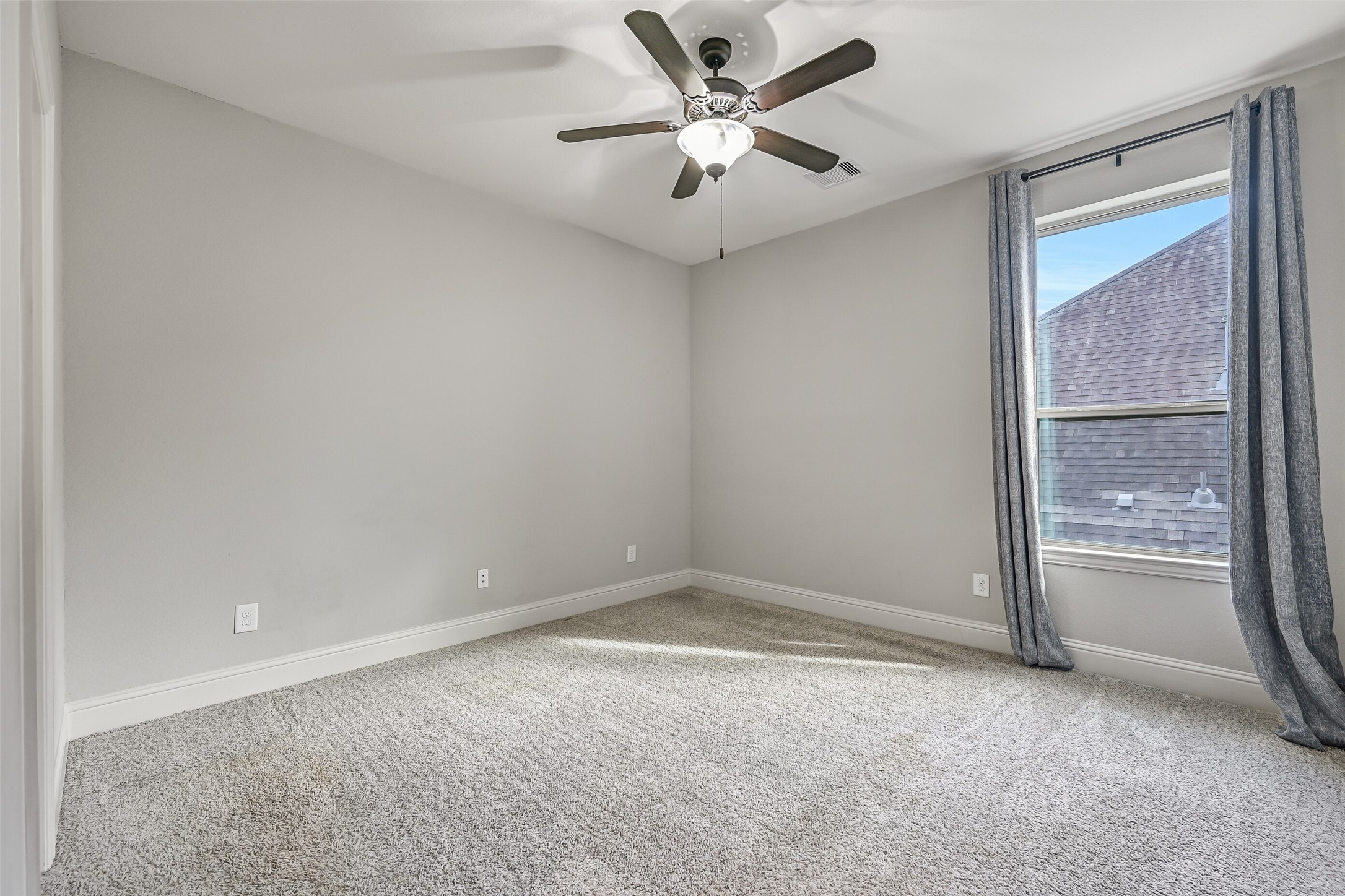 The final upstairs bedroom offers plush carpeting, neutral paint, a lighted ceiling fan & a side-facing window with draperies. A walk-in closet completes the room, with easy access to the shared hallway bathroom.