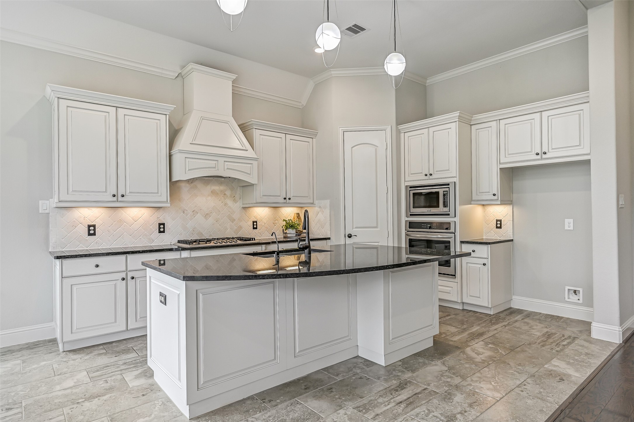 The kitchen is a stunner! An oversized granite island takes center stage, surrounded by inked white cabinetry, a herringbone brick backsplash, custom pendant lighting & undercabinet illumination. You'll also find a 5-burner gas cooktop, built-in appliances & a walk-in pantry.