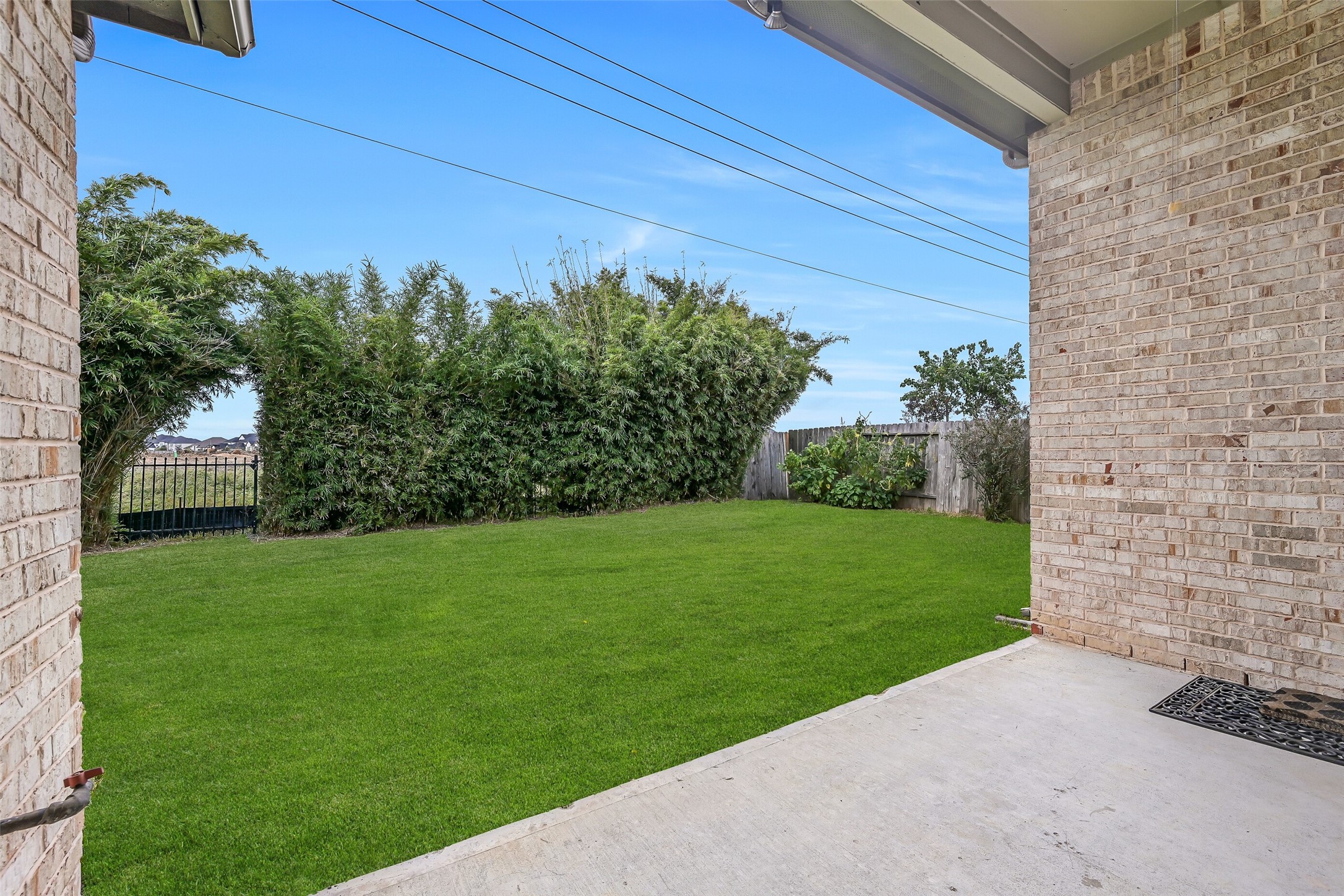 Step out onto the covered back patio, complete with a ceiling fan & gas stub for grilling! The spacious grassy backyard is framed by established bamboo along the rear fence, providing privacy-enhancing screening and a lovely green backdrop.