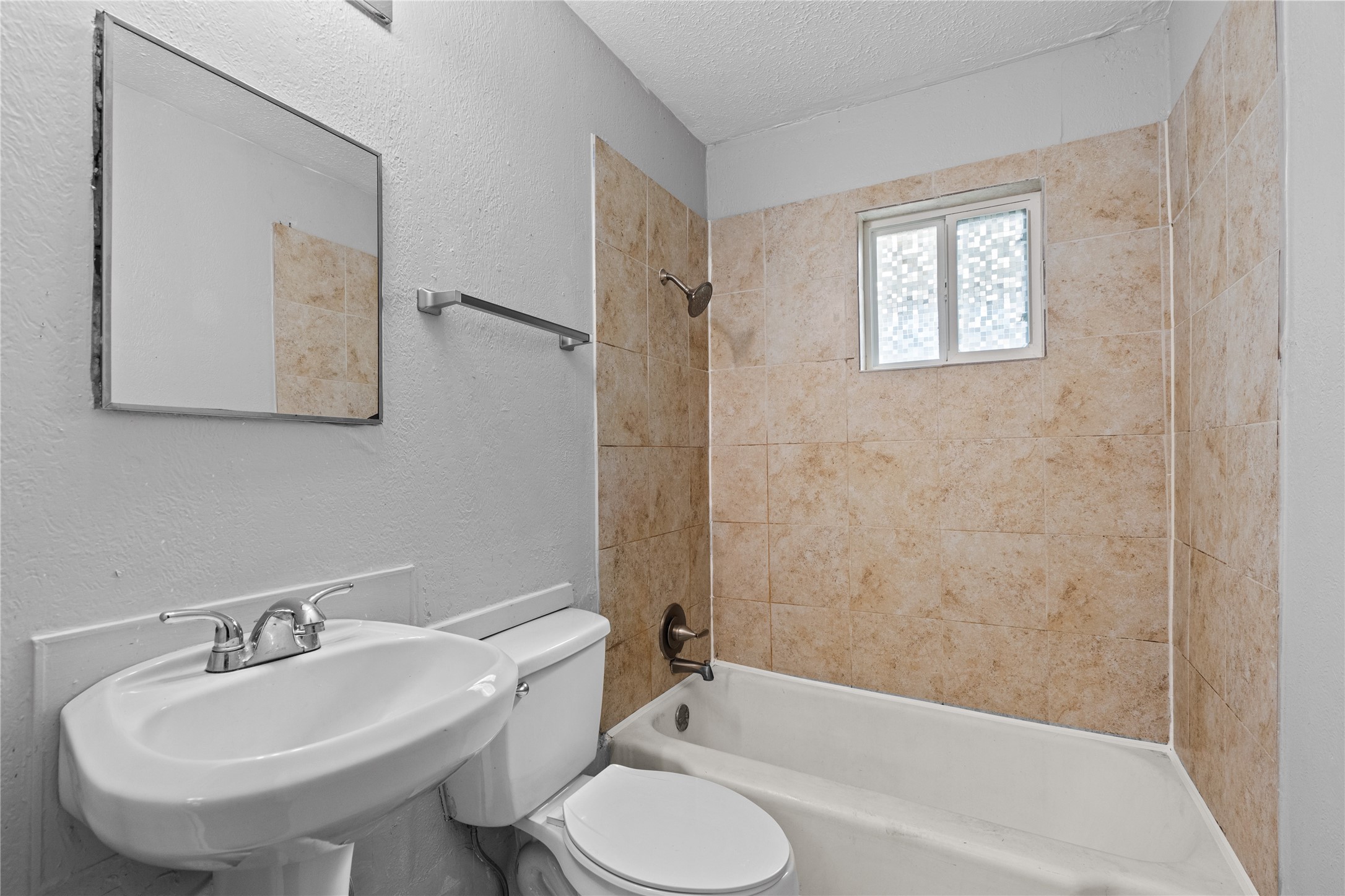 Bathroom with pedestal sink and tiled tub/shower combo
