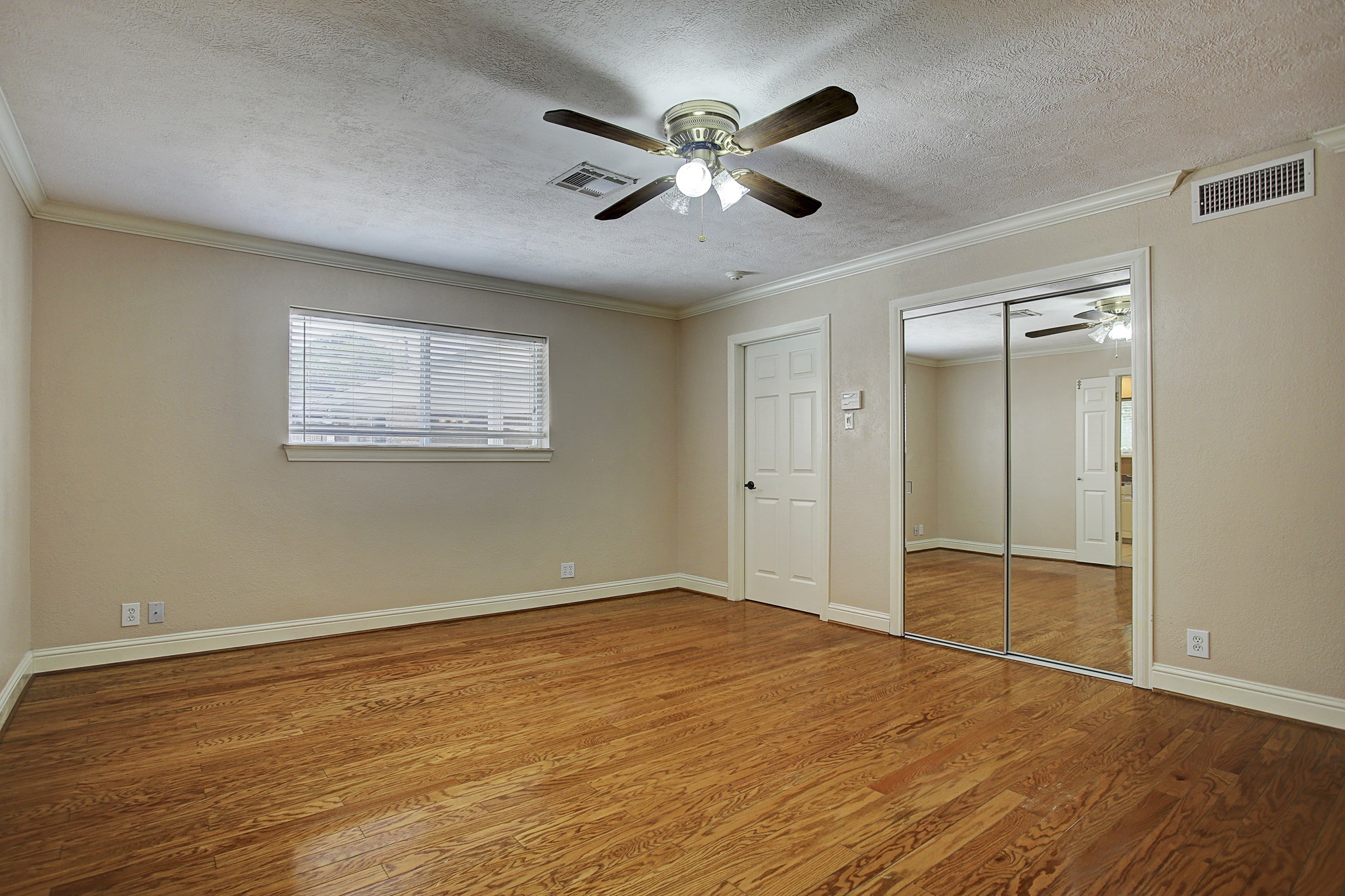 A secondary bedroom with mirrored closet doors, crown molding, and room to make yourself comfortable.
