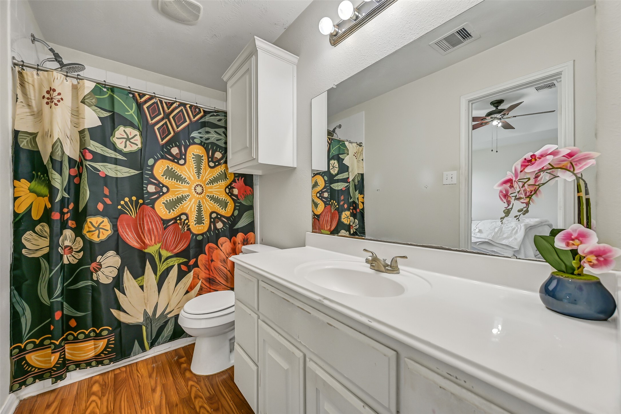 The en suite primary bath features a long vanity with abundant storage, expansive wall mirror, tub/shower combination, and additional upper cabinetry.