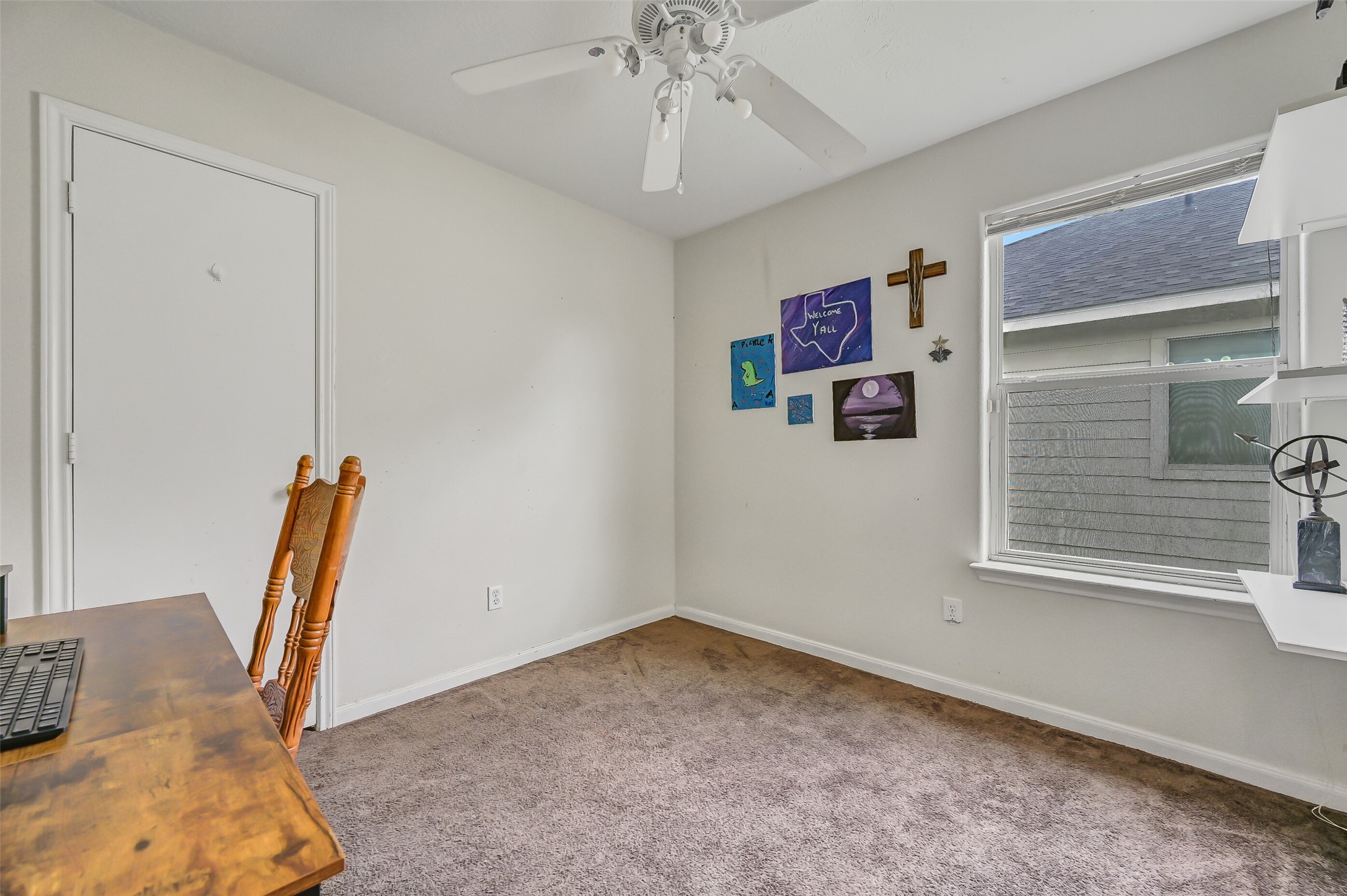 One of two secondary bedrooms offers a neutral palette, ceiling fan, natural light, and flexibility for use as a bedroom, home office, or hobby space.