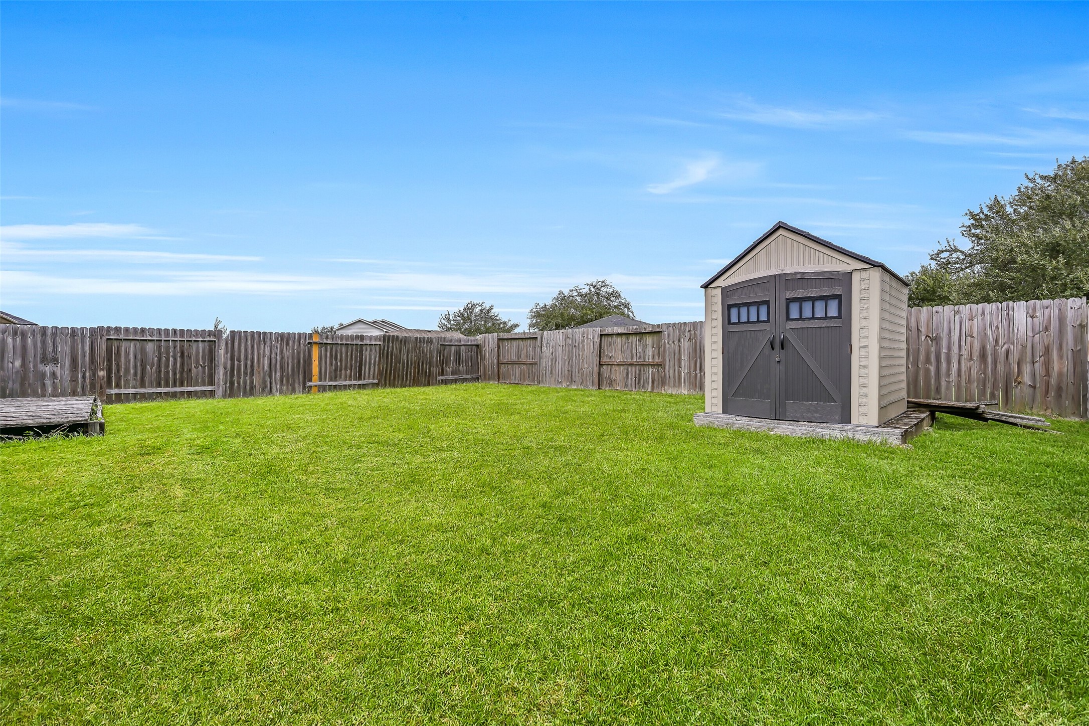 Another view emphasizes the generous backyard and freestanding storage shed, with plenty of open lawn remaining for recreation and outdoor activities.