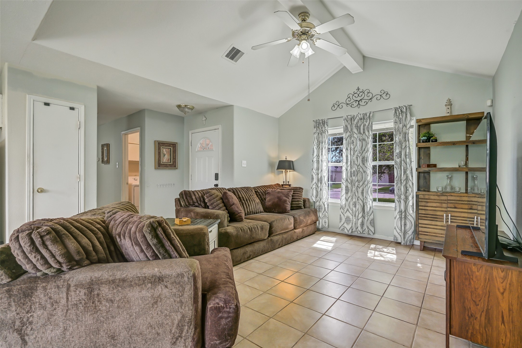The spacious family room is highlighted by a dramatic vaulted ceiling, ceiling fan, and a pair of windows that bring natural light into the heart of the home.