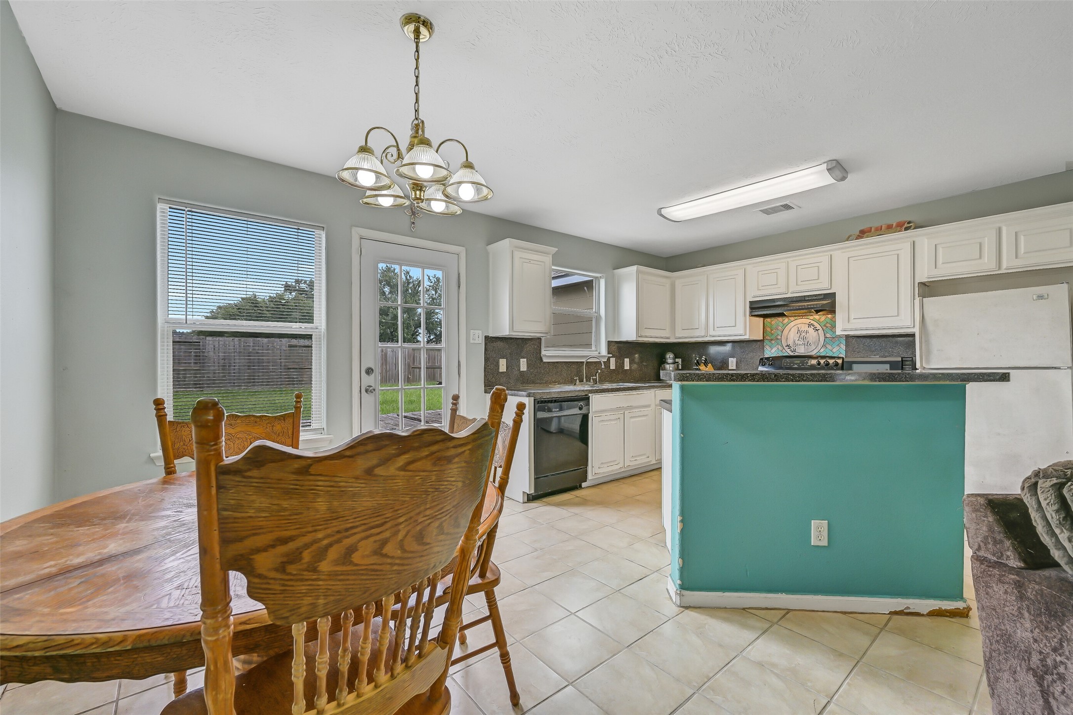 The open kitchen overlooks the dining and family rooms and features a breakfast bar peninsula, abundant cabinetry, generous counter space, and convenient backyard access nearby.