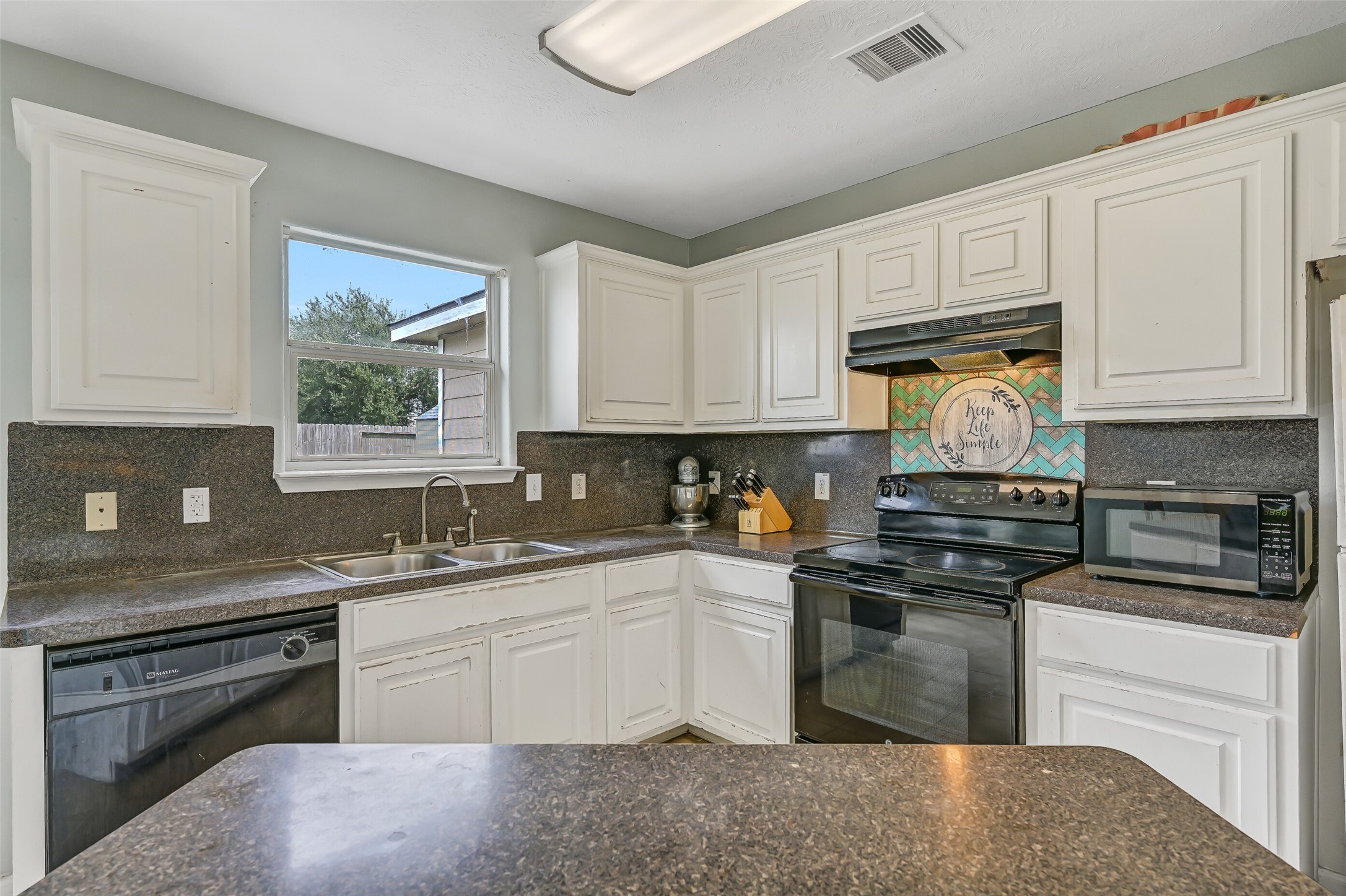 Plenty of cabinetry and counter space provide practical kitchen storage and prep room, while a window above the double-basin sink brings in natural light.
