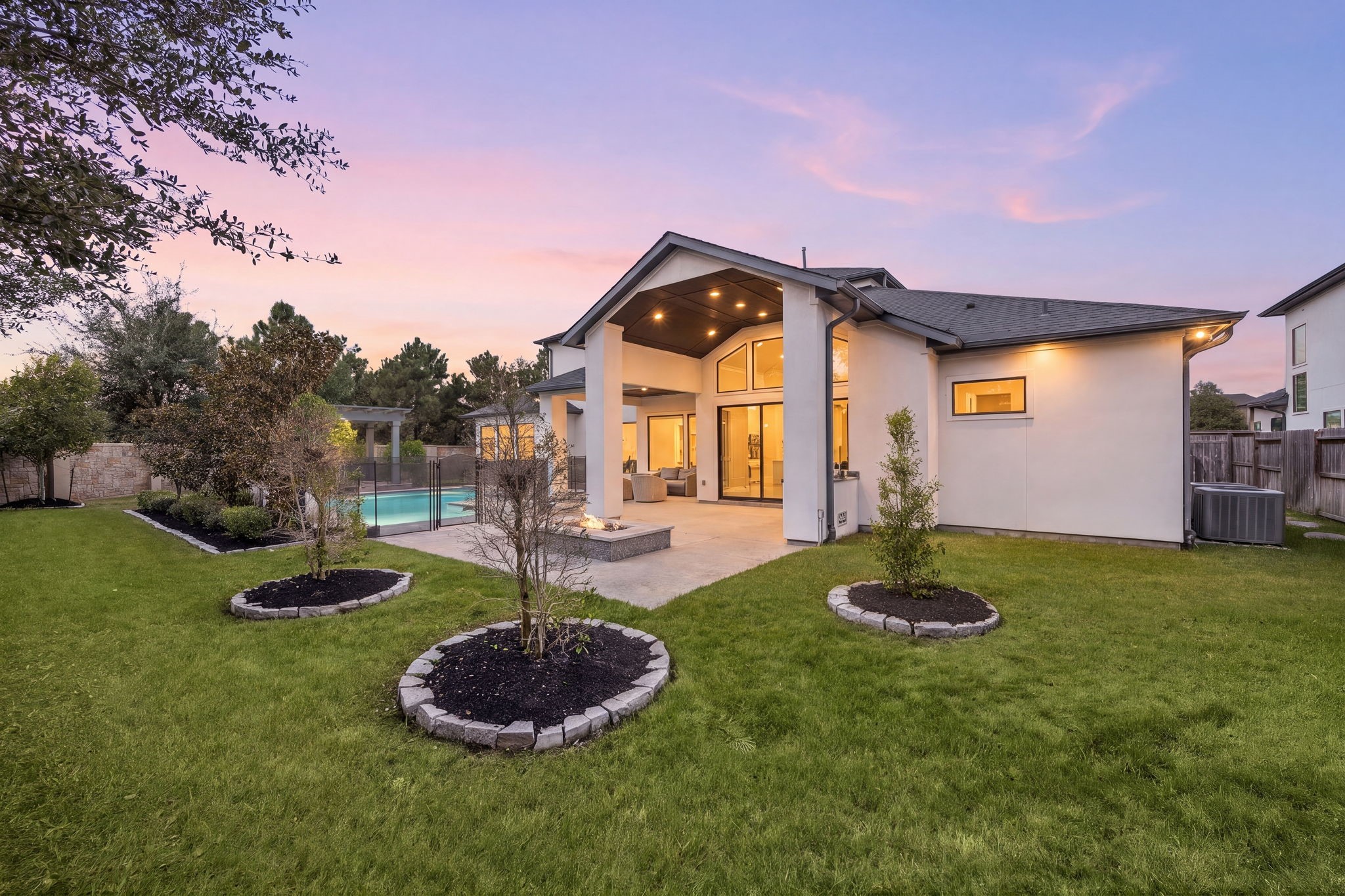 Gorgeous backyard showcasing manicured landscaping, a spacious lawn, and beautiful evening views of the home.