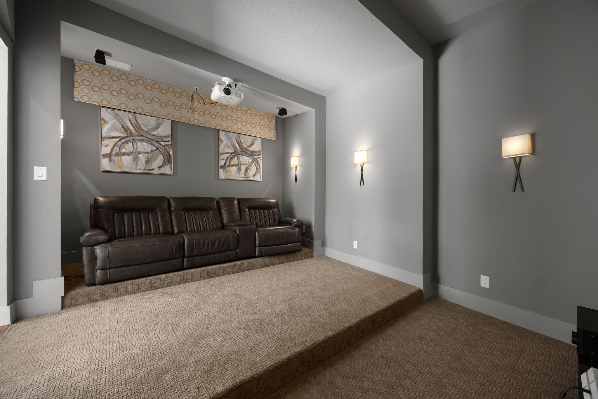 Dedicated media room with stylish accent walls, accent lighting, and a theater-inspired seating levels.