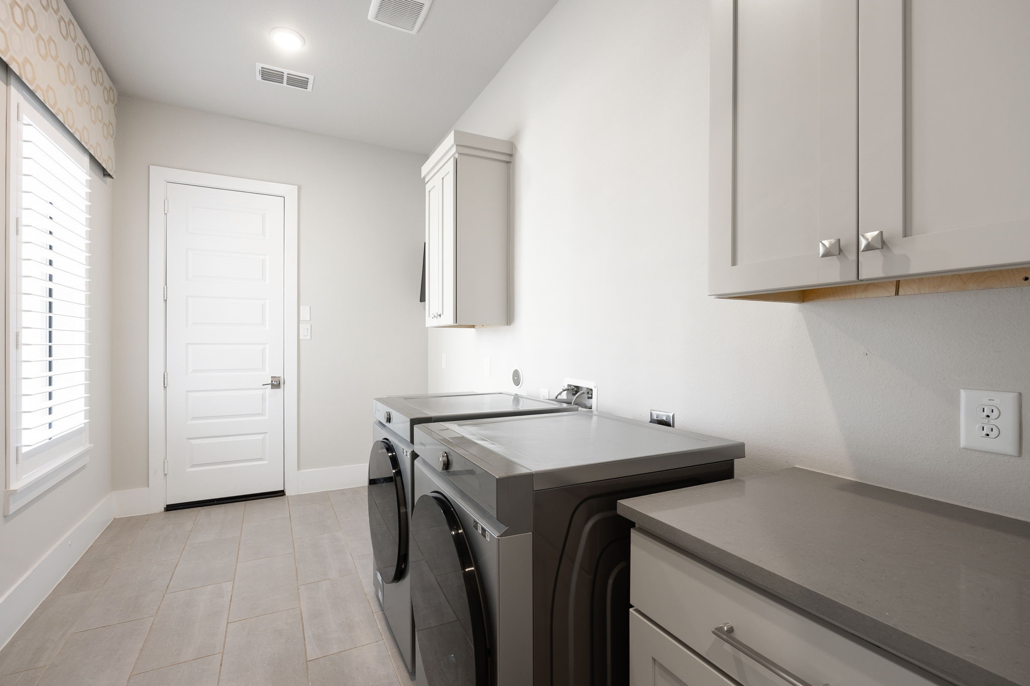 Convenient laundry room featuring built-in cabinetry, counter space, and room for everyday household needs.