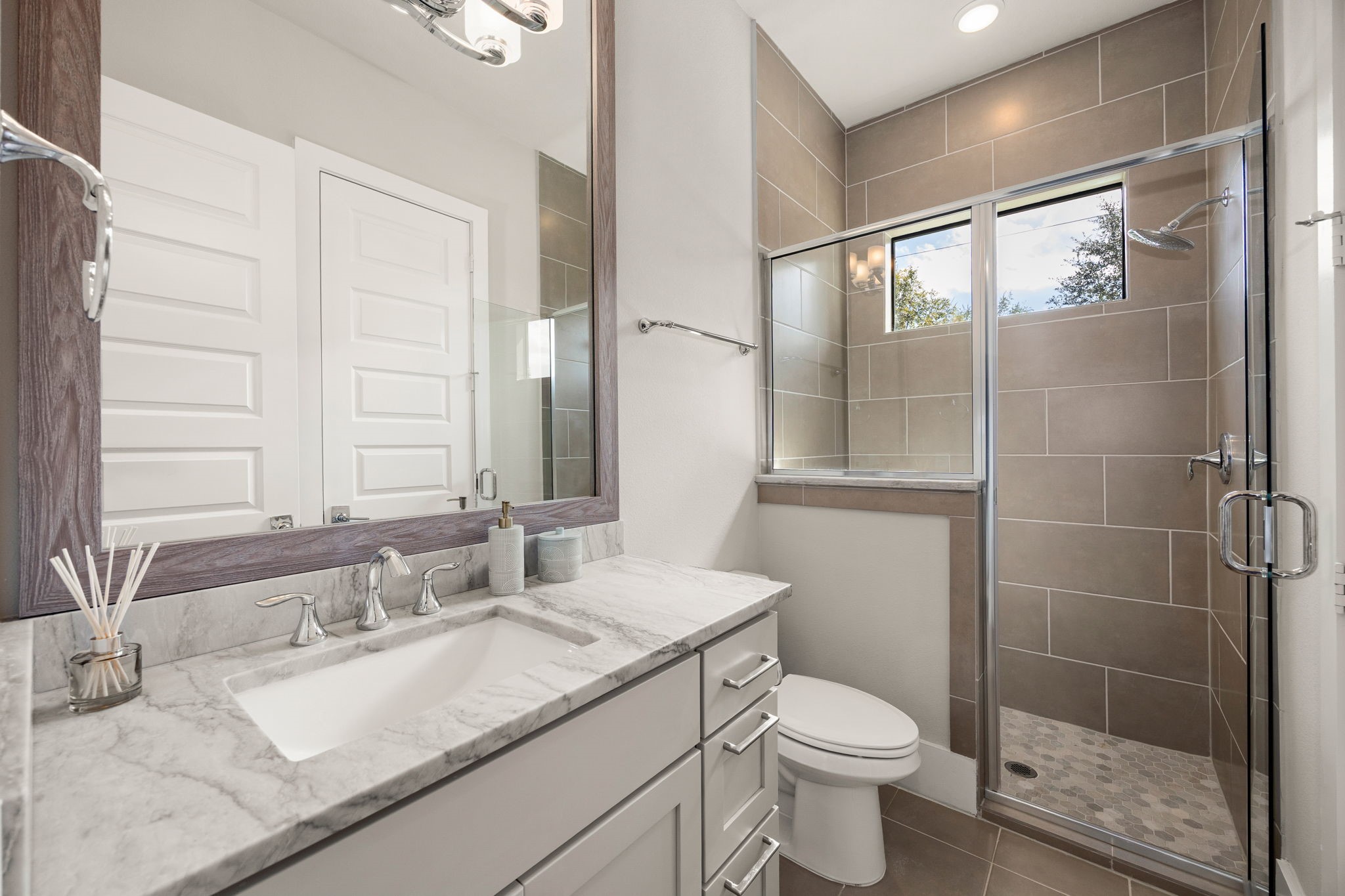 Beautifully designed bathroom featuring a spacious vanity, stylish finishes, and an enclosed shower.