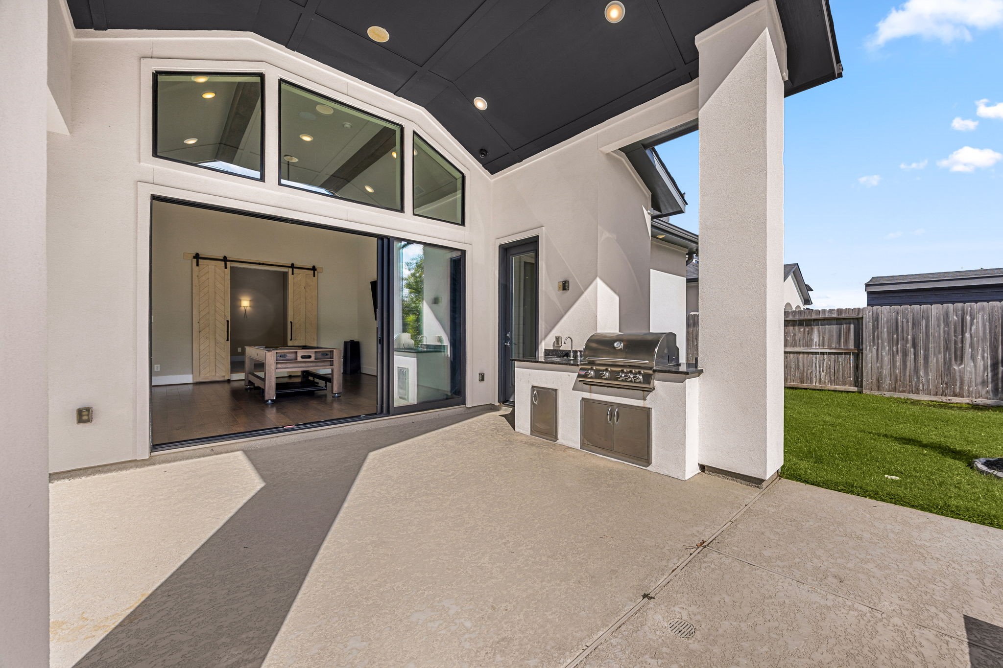 Additional covered area featuring beautiful architectural details and a built in outdoor kitchen with grill and sink, perfect for entertaining.