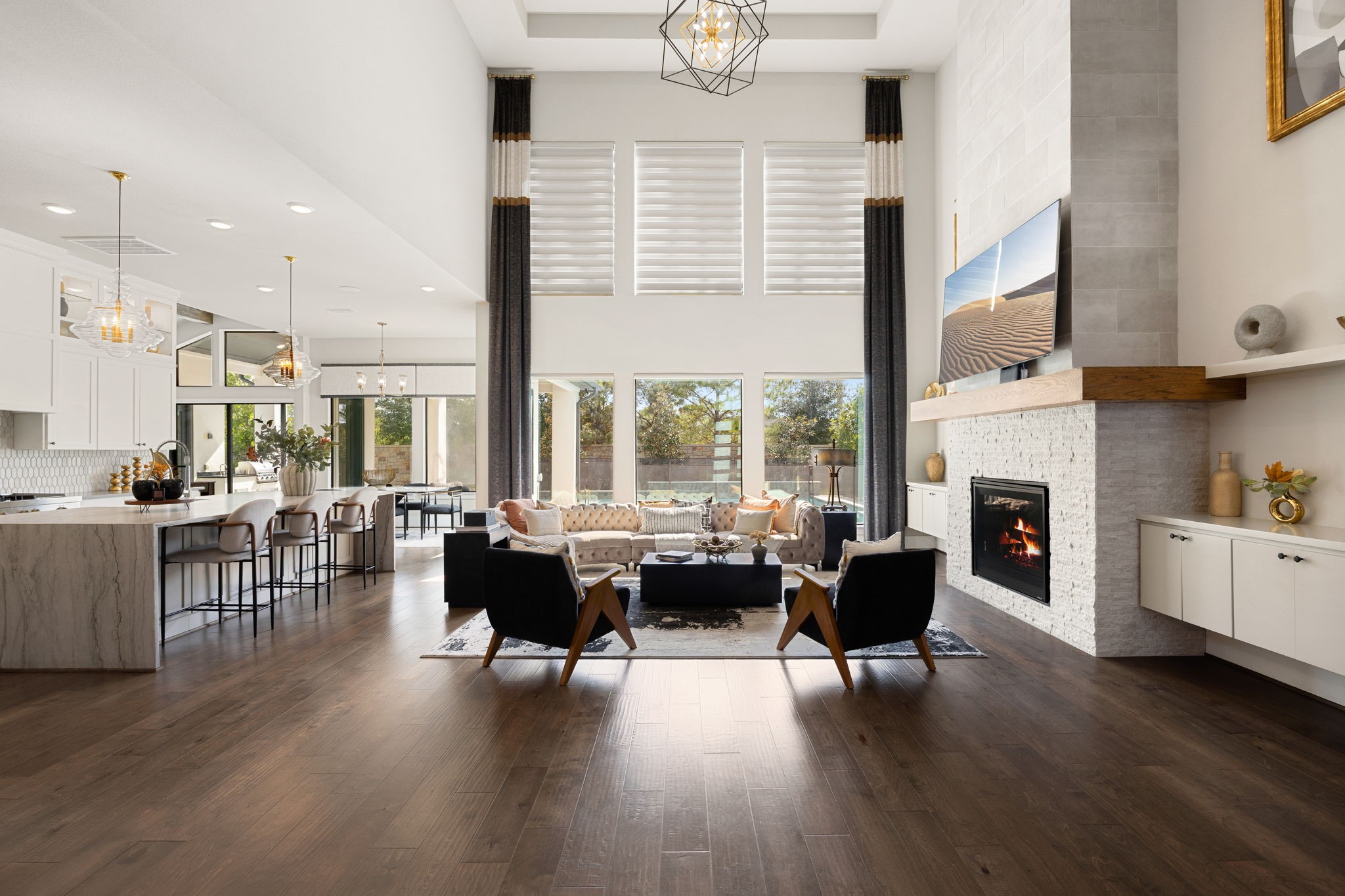 Spectacular living room featuring soaring ceilings, expansive two-story windows, and a beautiful stone and tile fireplace with wraparound wood mantle.