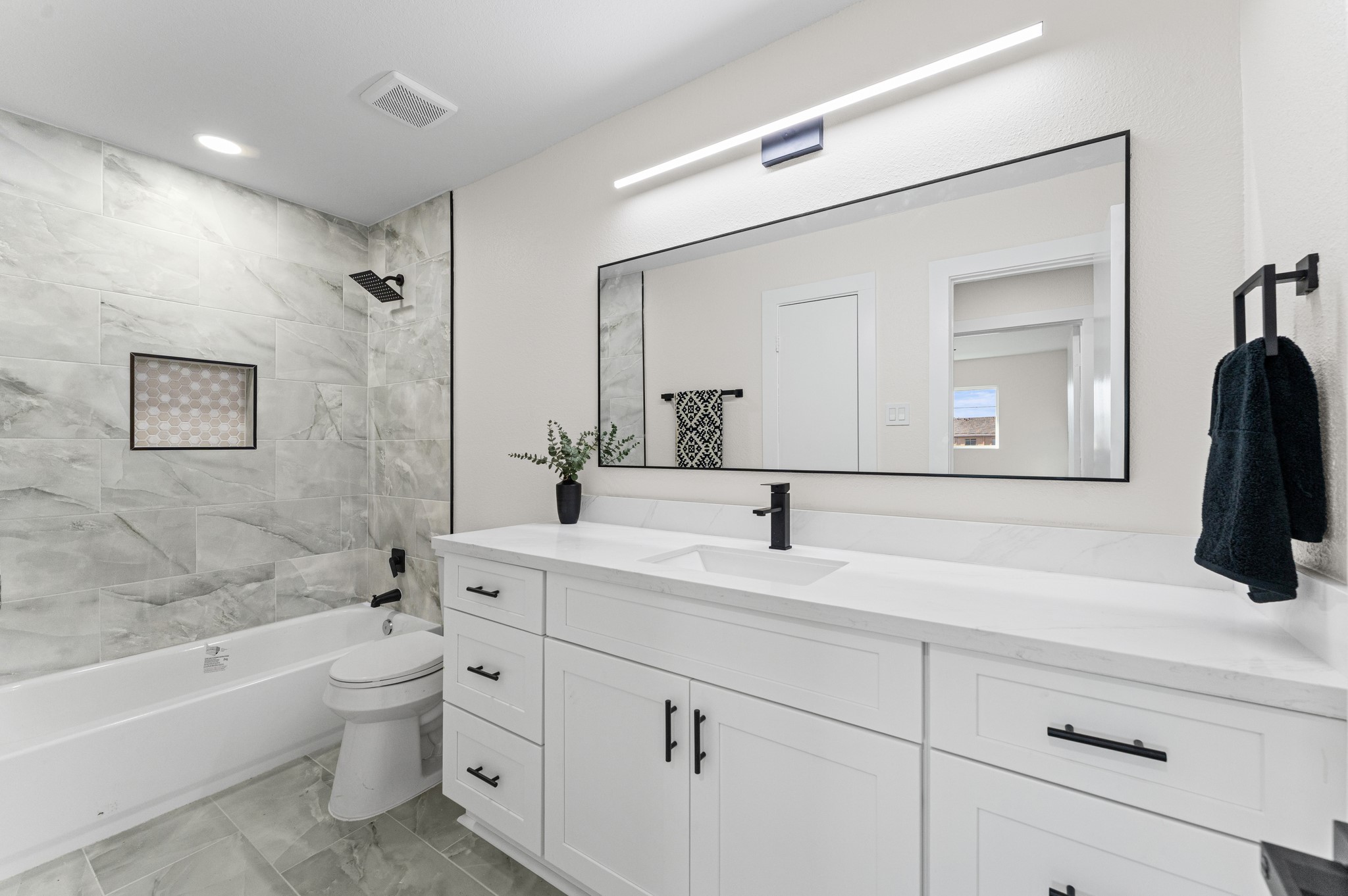 The secondary bathroom has been updated with a new tiled shower and brand-new tub combo, new quartz countertops, a new toilet, and new cabinets.