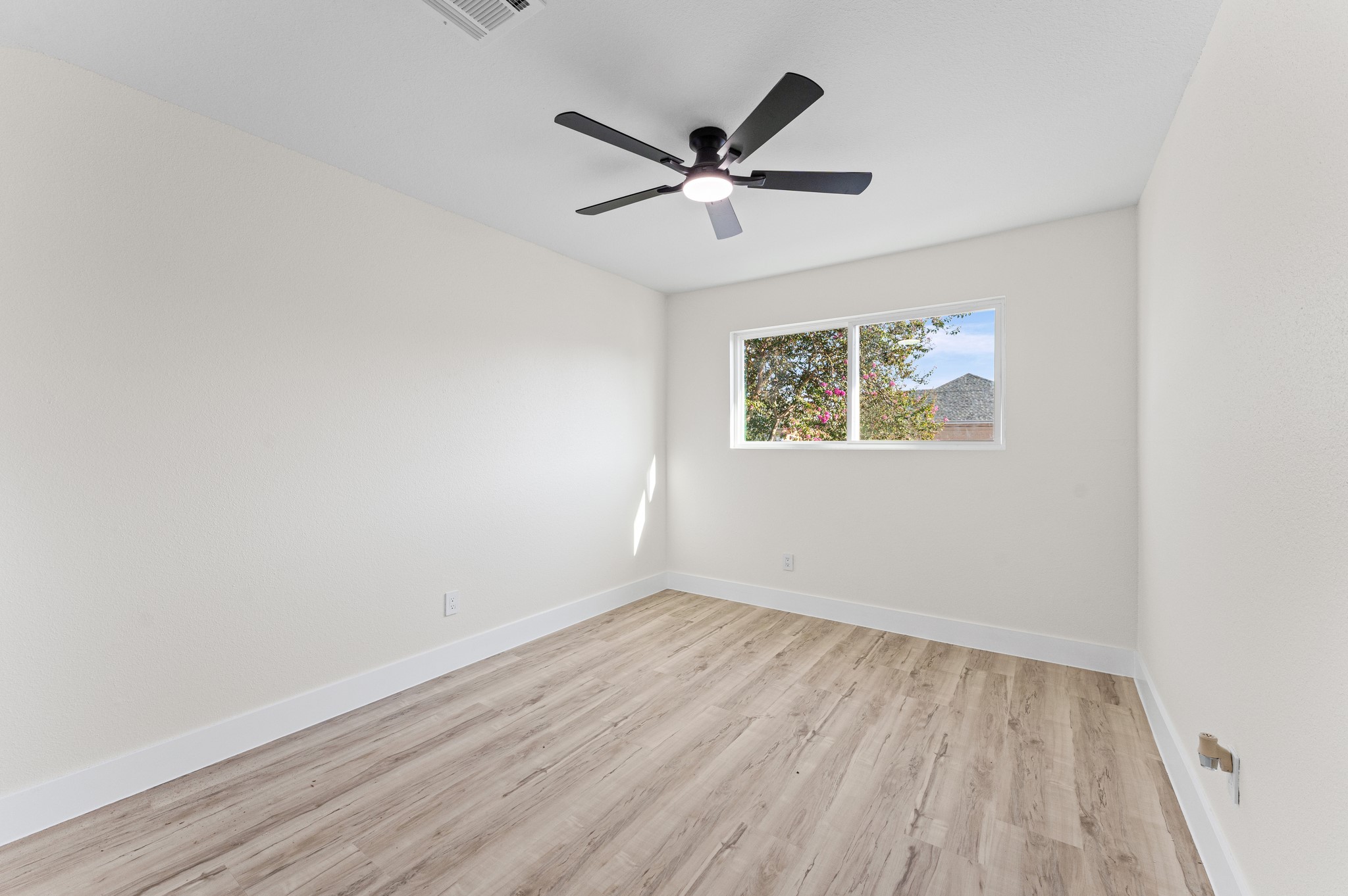 One of the secondary bedrooms, with updated flooring, windows, and a new fan.