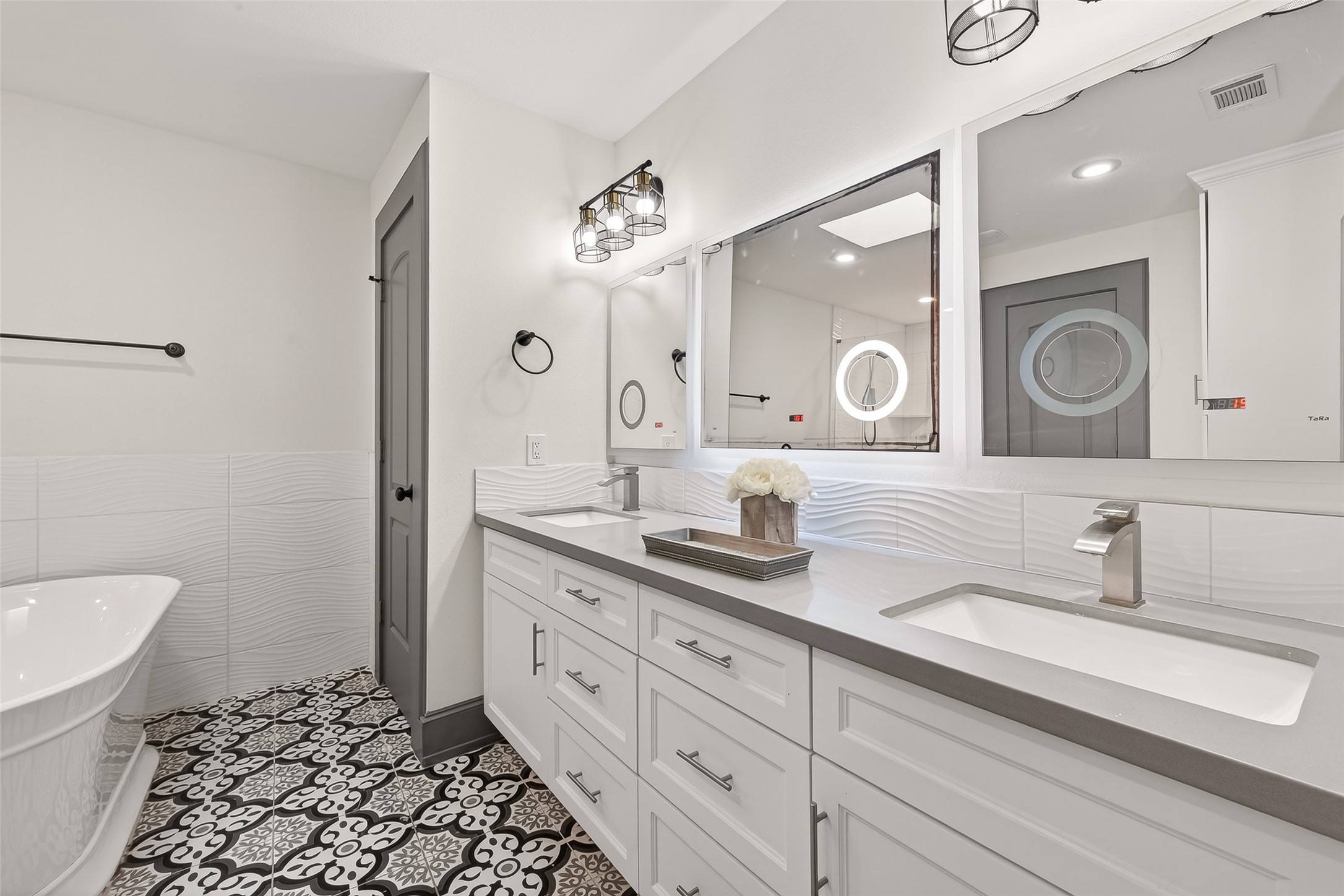 The dual-sink vanity offers ample storage, while patterned floor tiles add a touch of elegance.