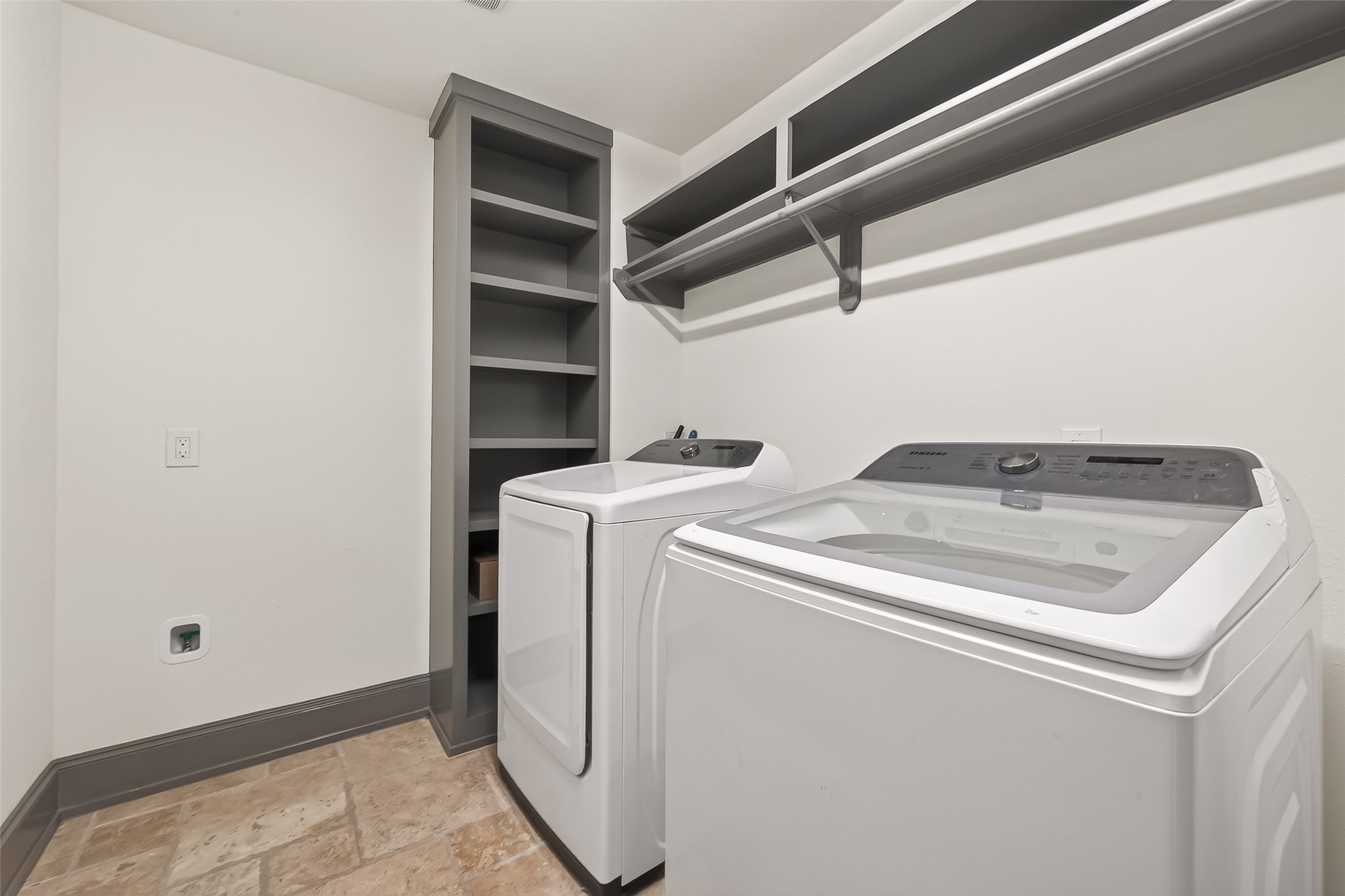 laundry room featuring a washer and dryer set, with built-in shelving and a hanging rod for convenience.