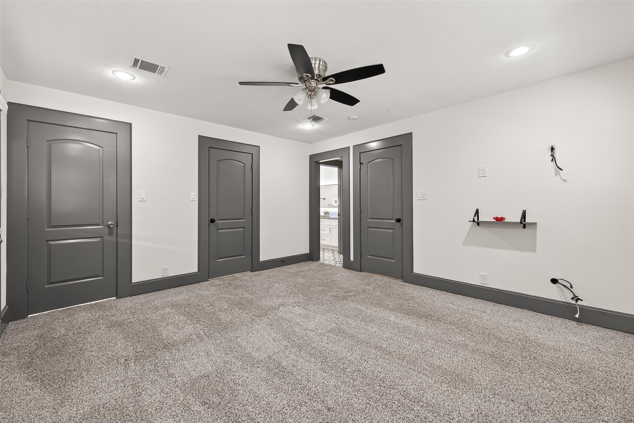 It includes a ceiling fan and a small wall shelf. The neutral color scheme offers a modern, clean look, perfect for a bedroom or office space.