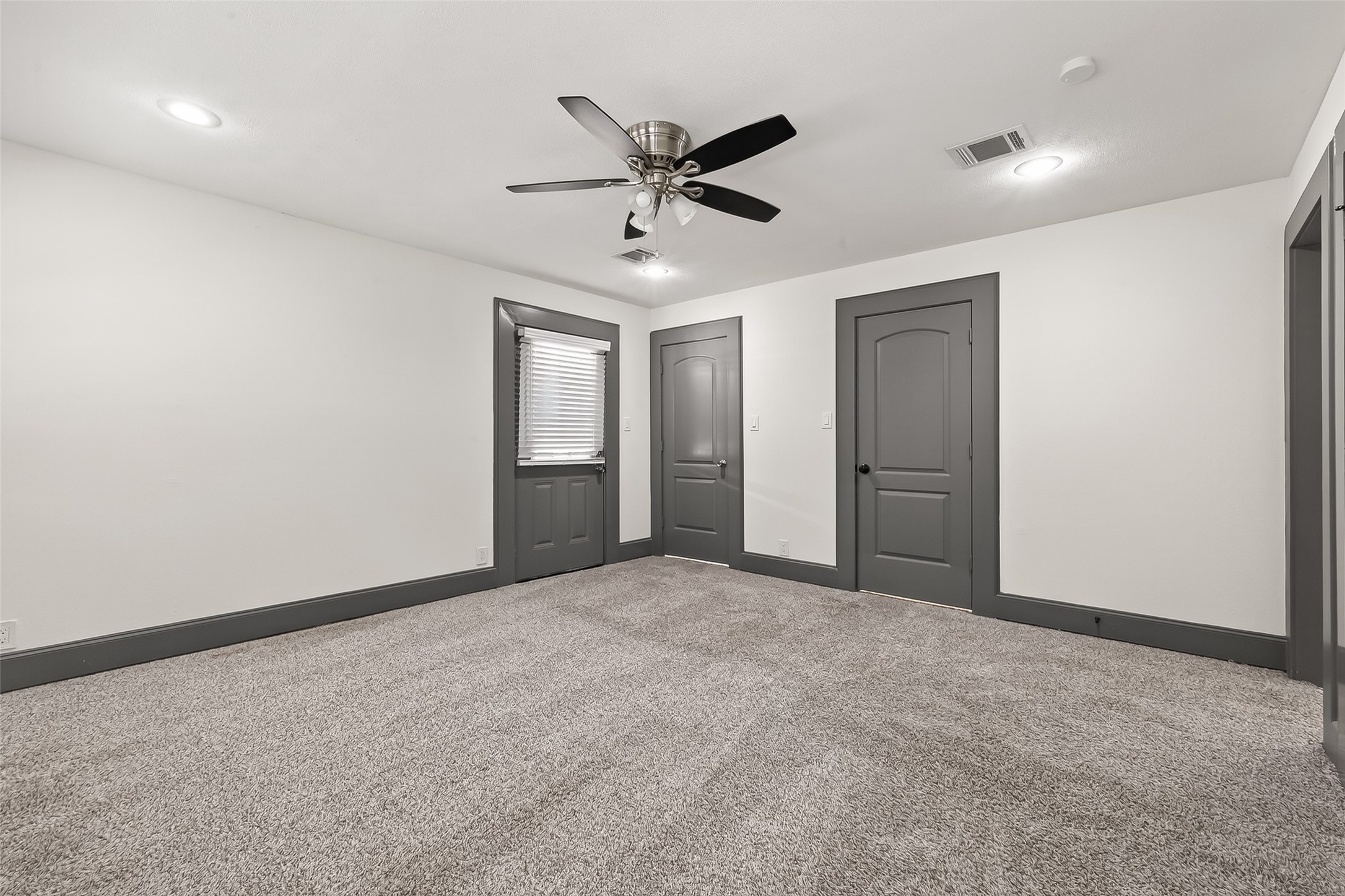 This room features neutral walls and carpeting, accented by dark trim and doors.