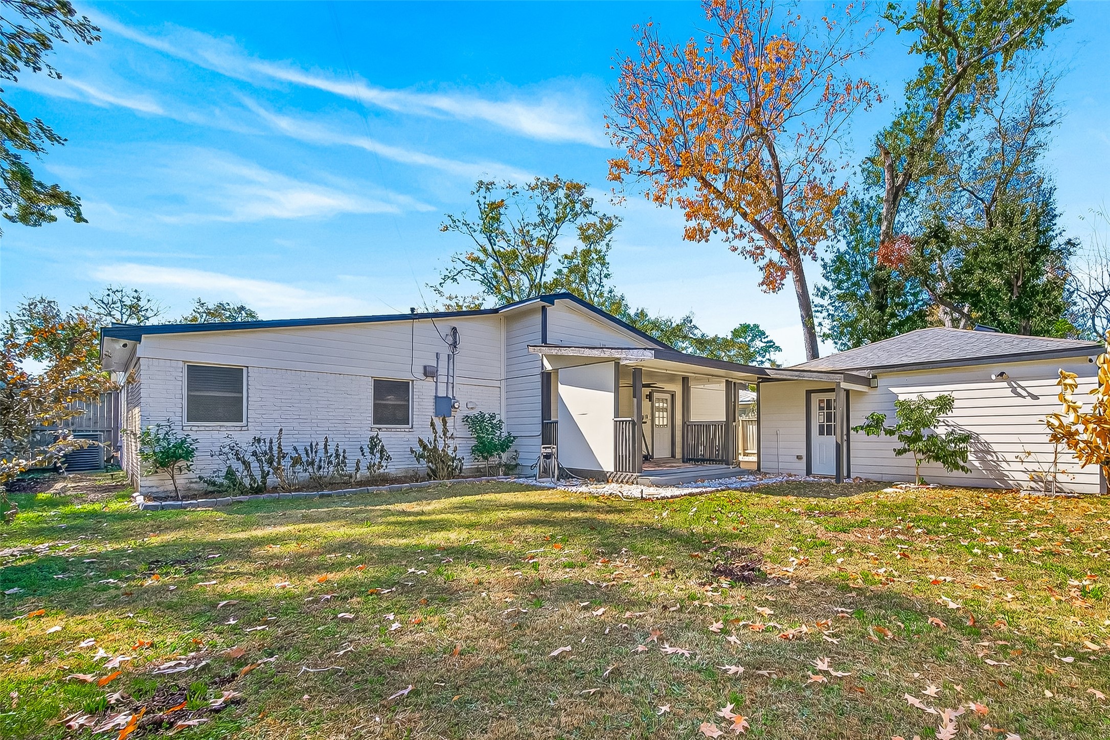 Single-story home with a spacious backyard, mature trees, and a covered patio area.