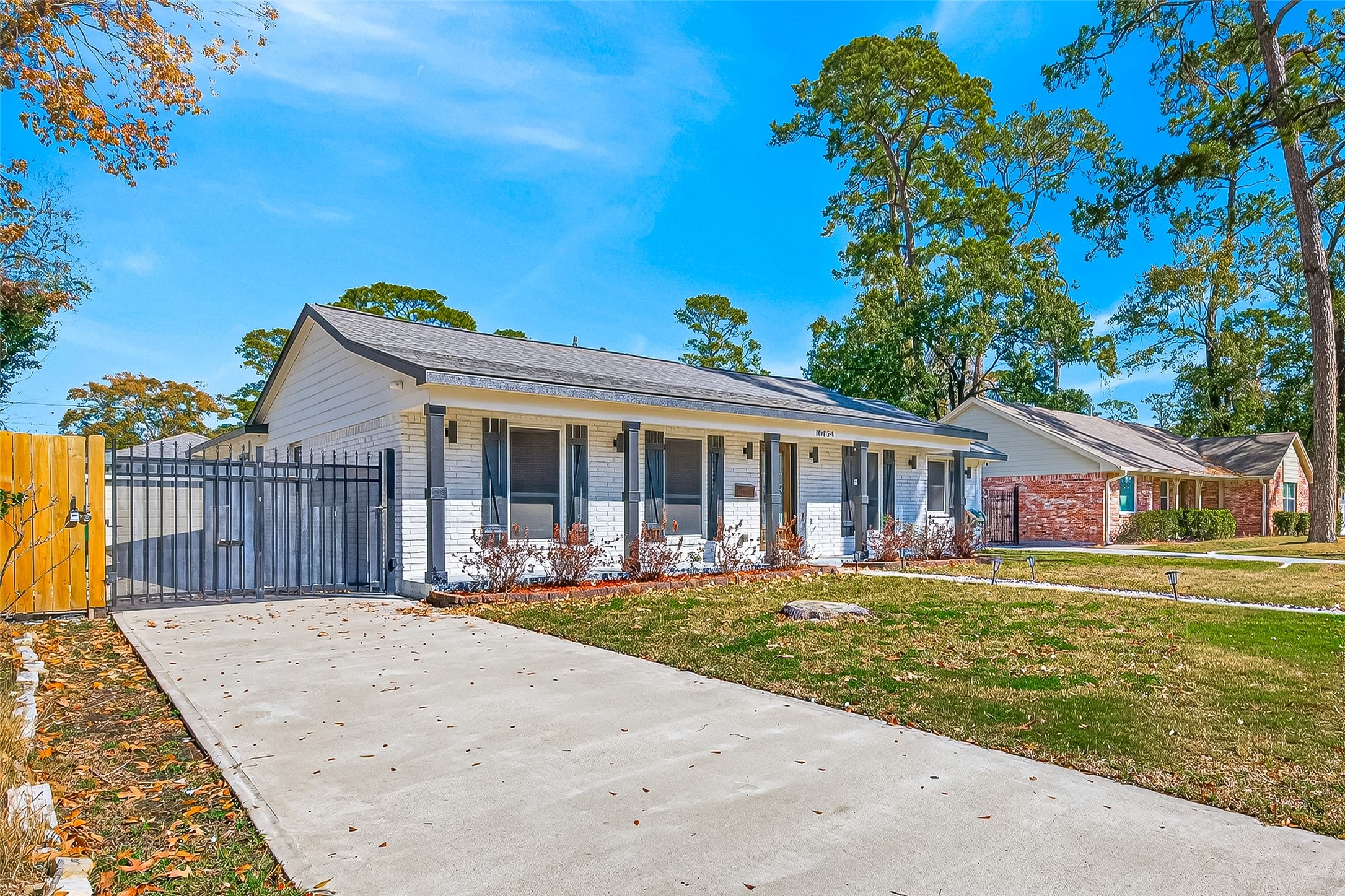 It has a neatly maintained front yard and a long driveway leading to a gated side entrance.