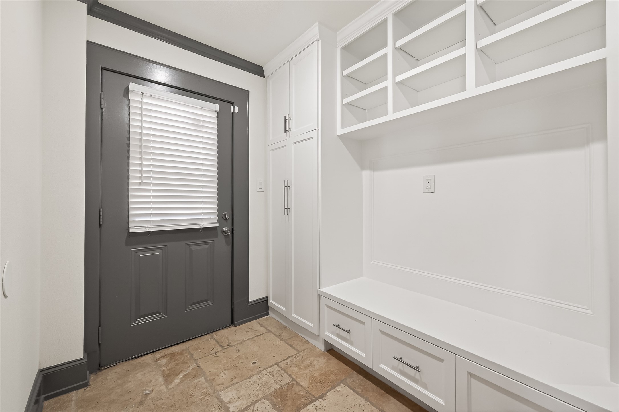 It features a built-in bench with storage drawers, open shelving above, and a tiled floor, providing a functional entryway space.