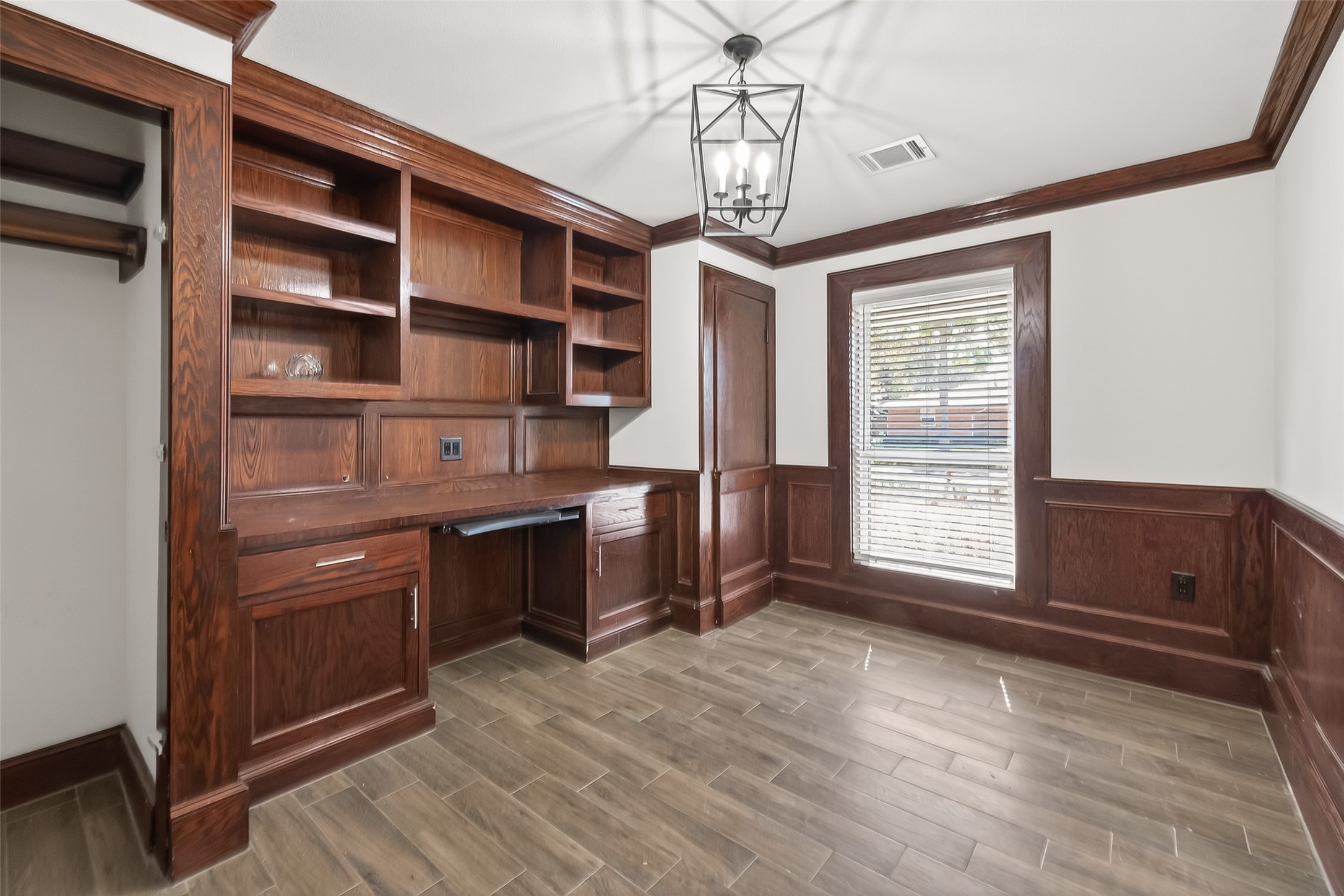 This room has elegant dark wood paneling and built-in shelving with a workspace.