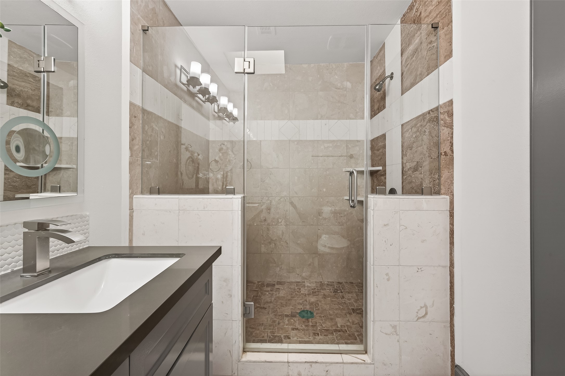The vanity includes a sleek sink with contemporary fixtures, complemented by a well-lit mirror.
