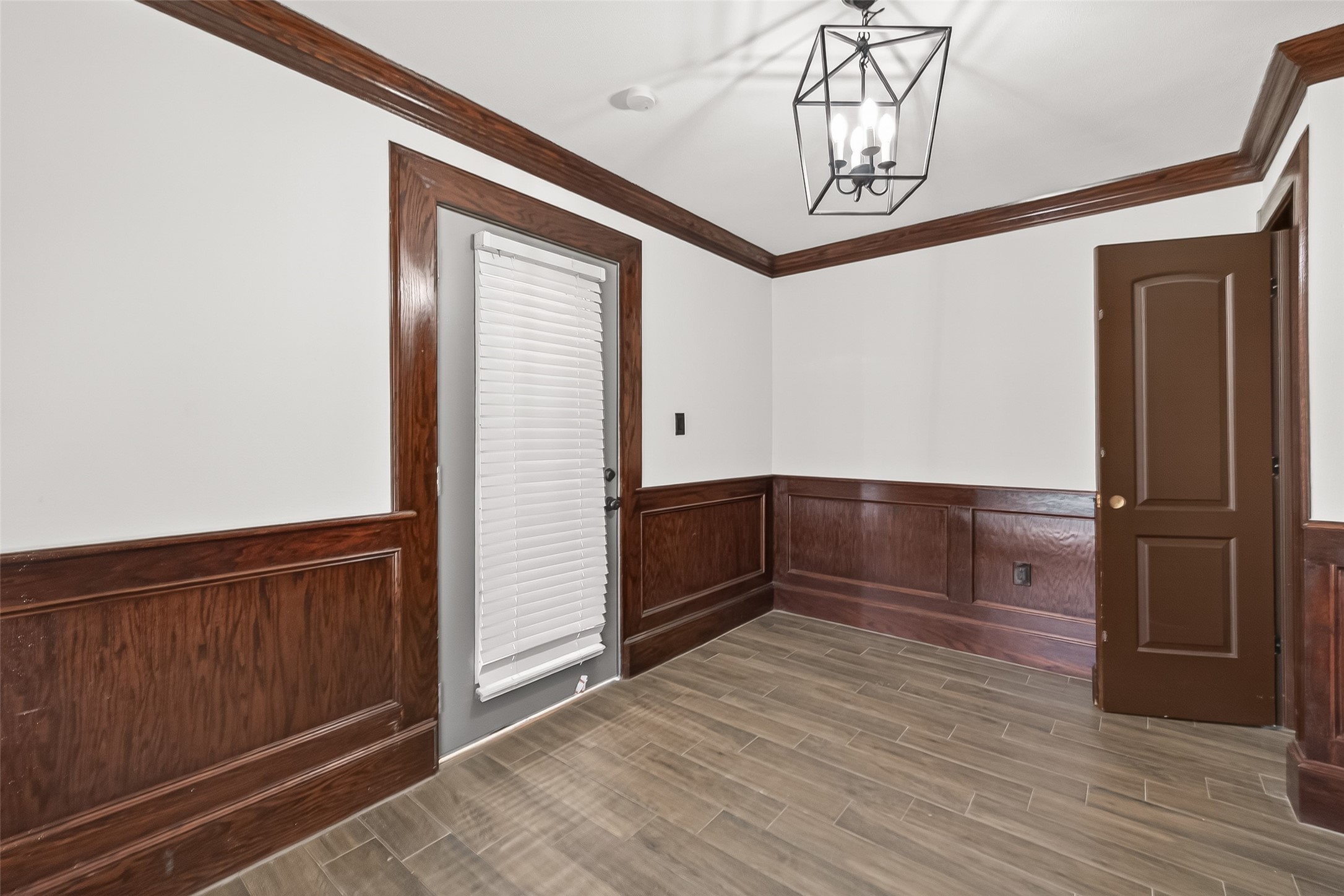 This room features elegant wood paneling and trim, a modern light fixture, and tile flooring, creating a classic and sophisticated ambiance.