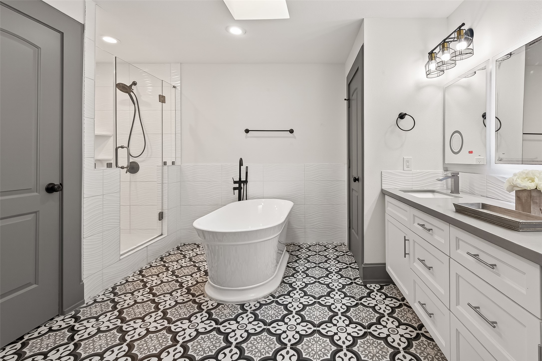 This bathroom features a sleek, modern design with a freestanding bathtub and a spacious glass-enclosed shower.