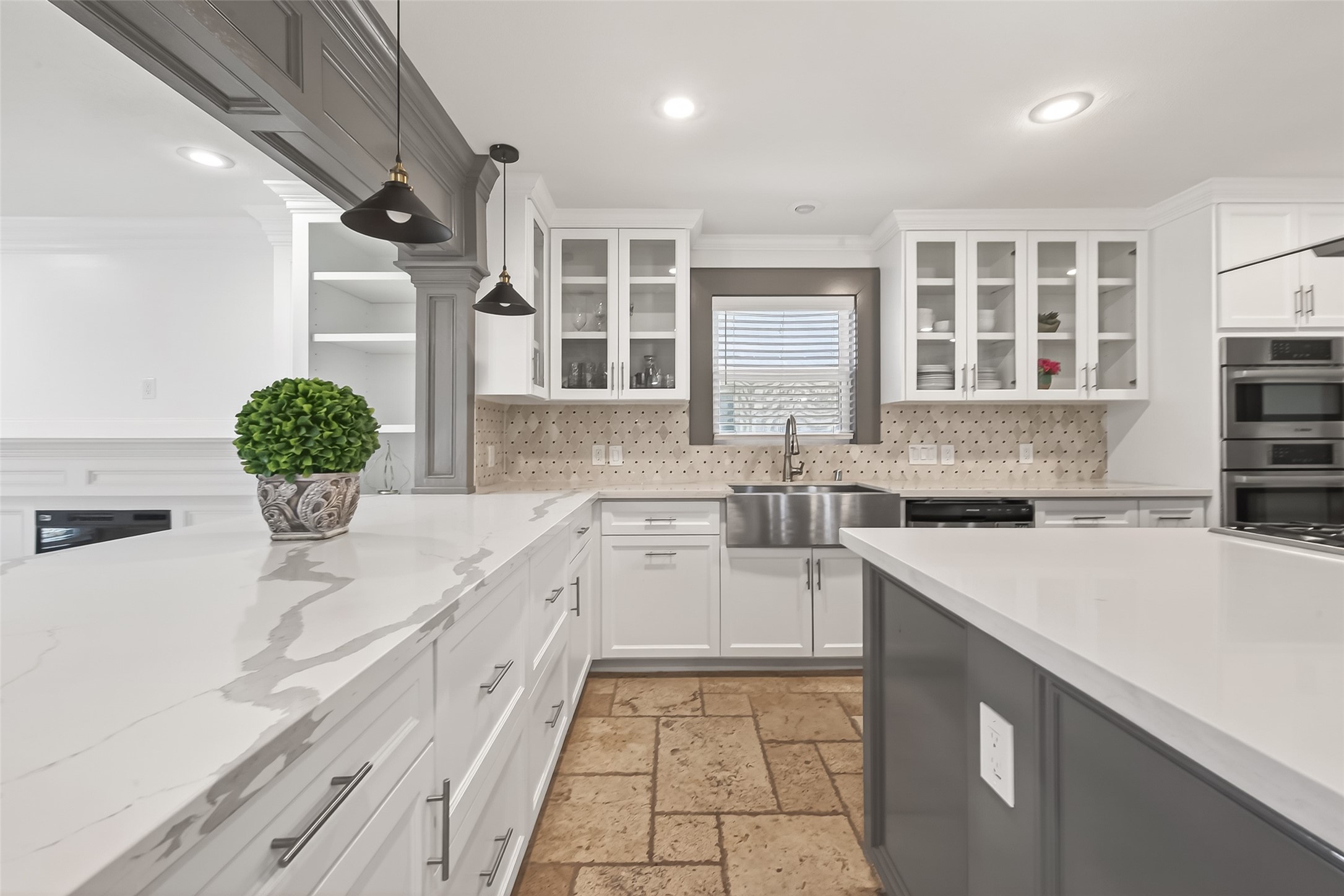 It has white cabinetry with glass fronts, a farmhouse sink, and a stylish tile backsplash.