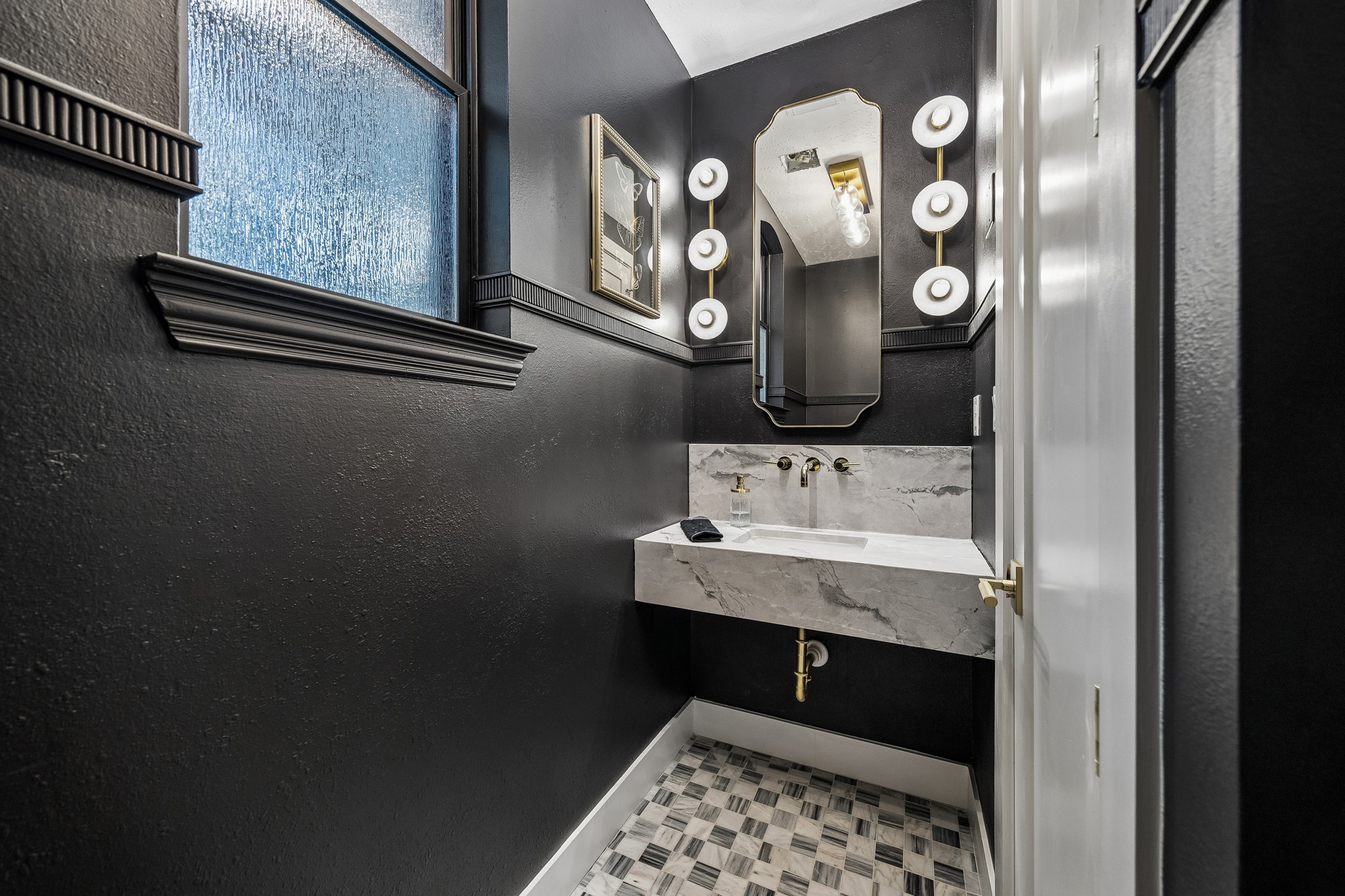 Dramatic half bath with a floating marble sink, wall mounted fixture, designer sconces and flooring