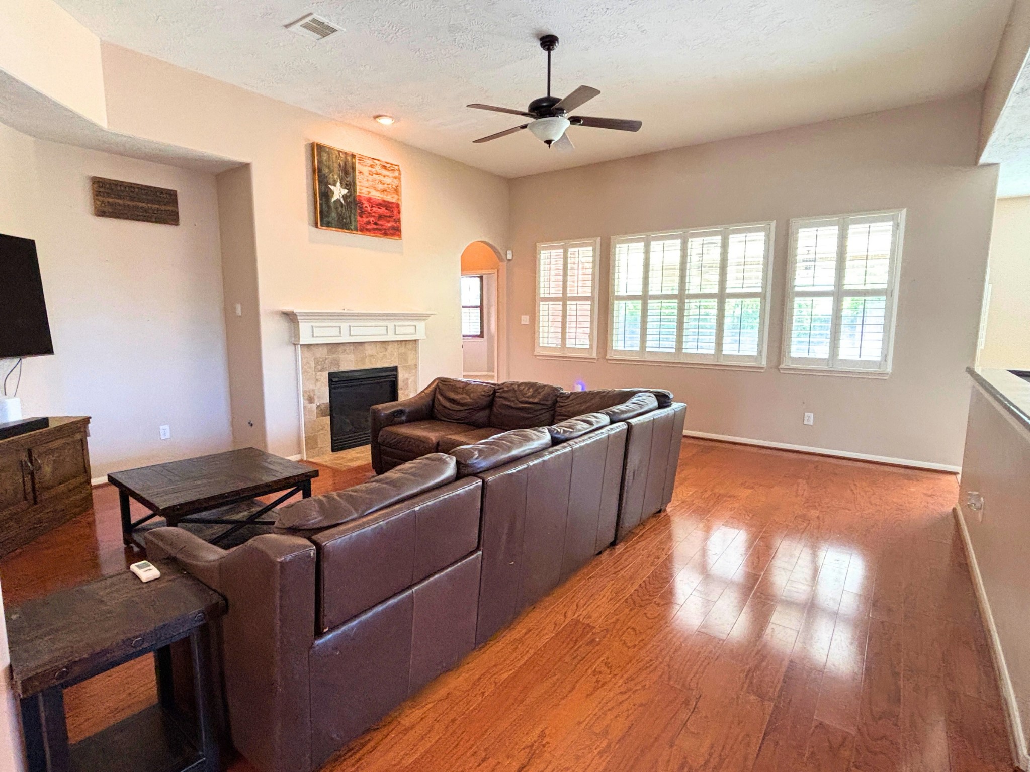 Spacious living room with hardwood floors, a gaslog fireplace, and abundant natural light.