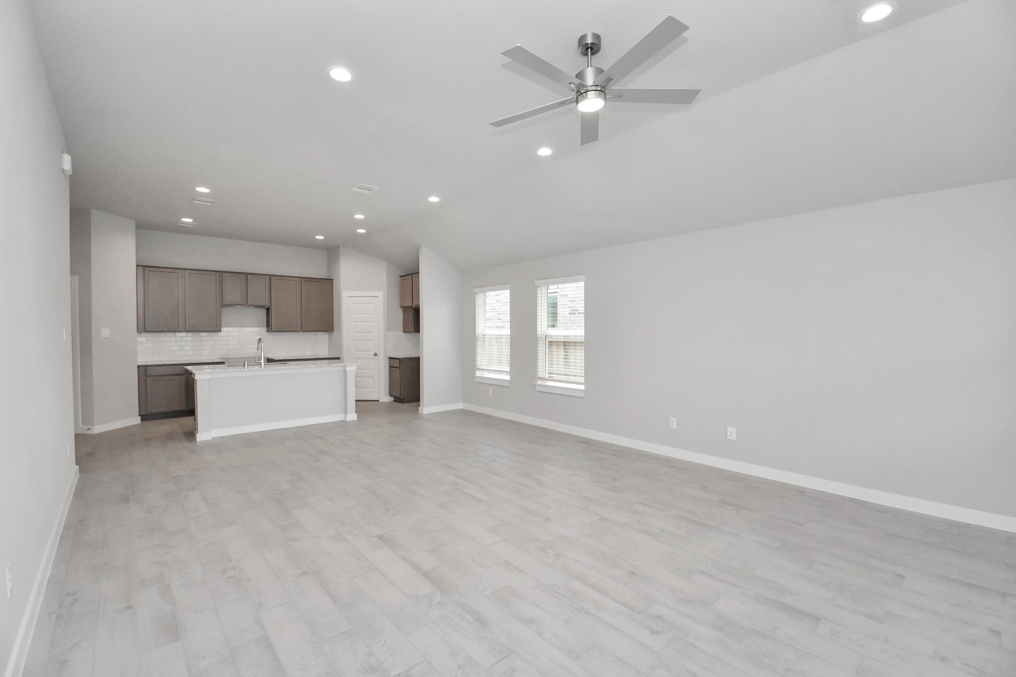 Bring your loved ones and guests together in the inviting living room! Boasting lofty high ceilings, recessed lighting, a stylish ceiling fan, custom paint, stunning flooring, and expansive windows that flood the space with ample natural light all day long. Sample photo of completed home with similar floor plan. Actual colors and selections may vary.