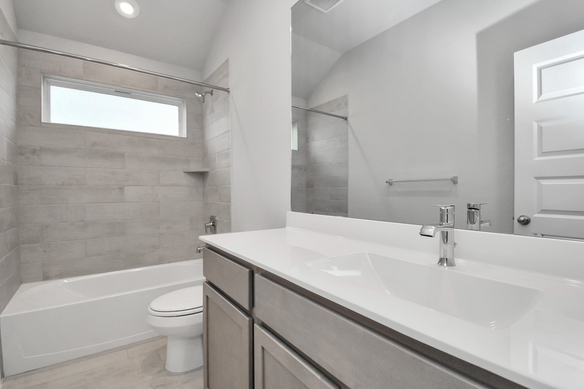 Secondary bath features tile flooring, bath/shower combo with tile surround, light stained wood cabinets, beautiful light countertop. Sample photo of completed home with similar floor plan. Actual colors and selections may vary.