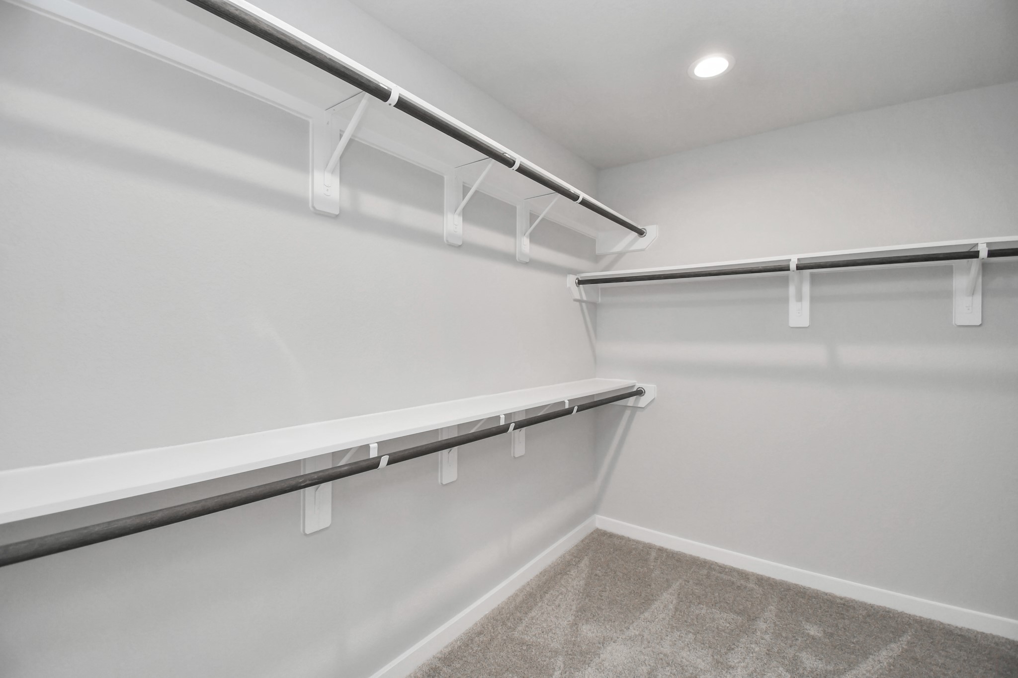 Walk-in closet that epitomizes luxury and practicality. This generously sized space features built-in shelving, offering abundant room for impeccable organization. High ceilings and recessed lighting create a bright and welcoming ambiance. Sample photo of completed home with similar floor plan. Actual colors and selections may vary.