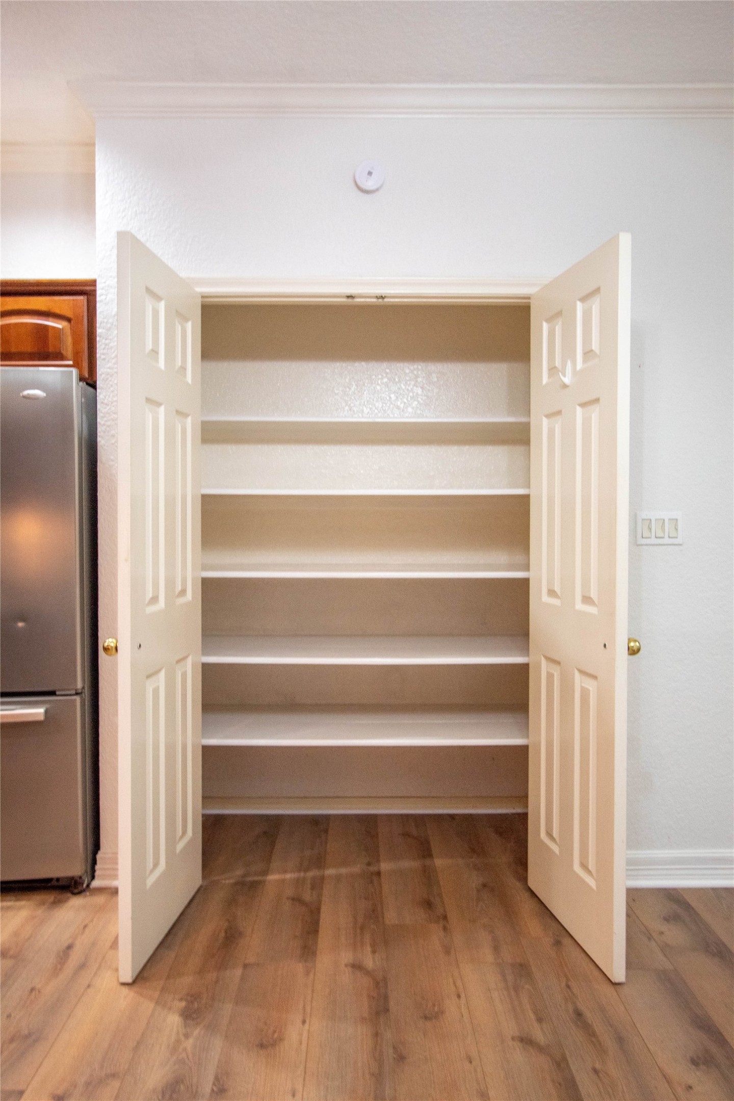The right side of the kitchen with double ovens, a refrigerator, table island and the pantry.