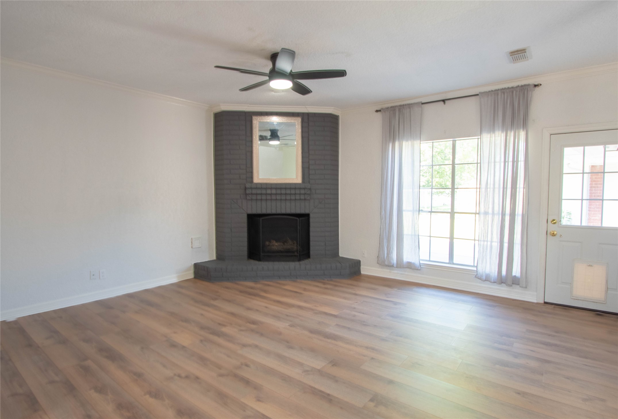 actual family room, gas log fireplace, laminated flooring, window overlooking at  the back patio