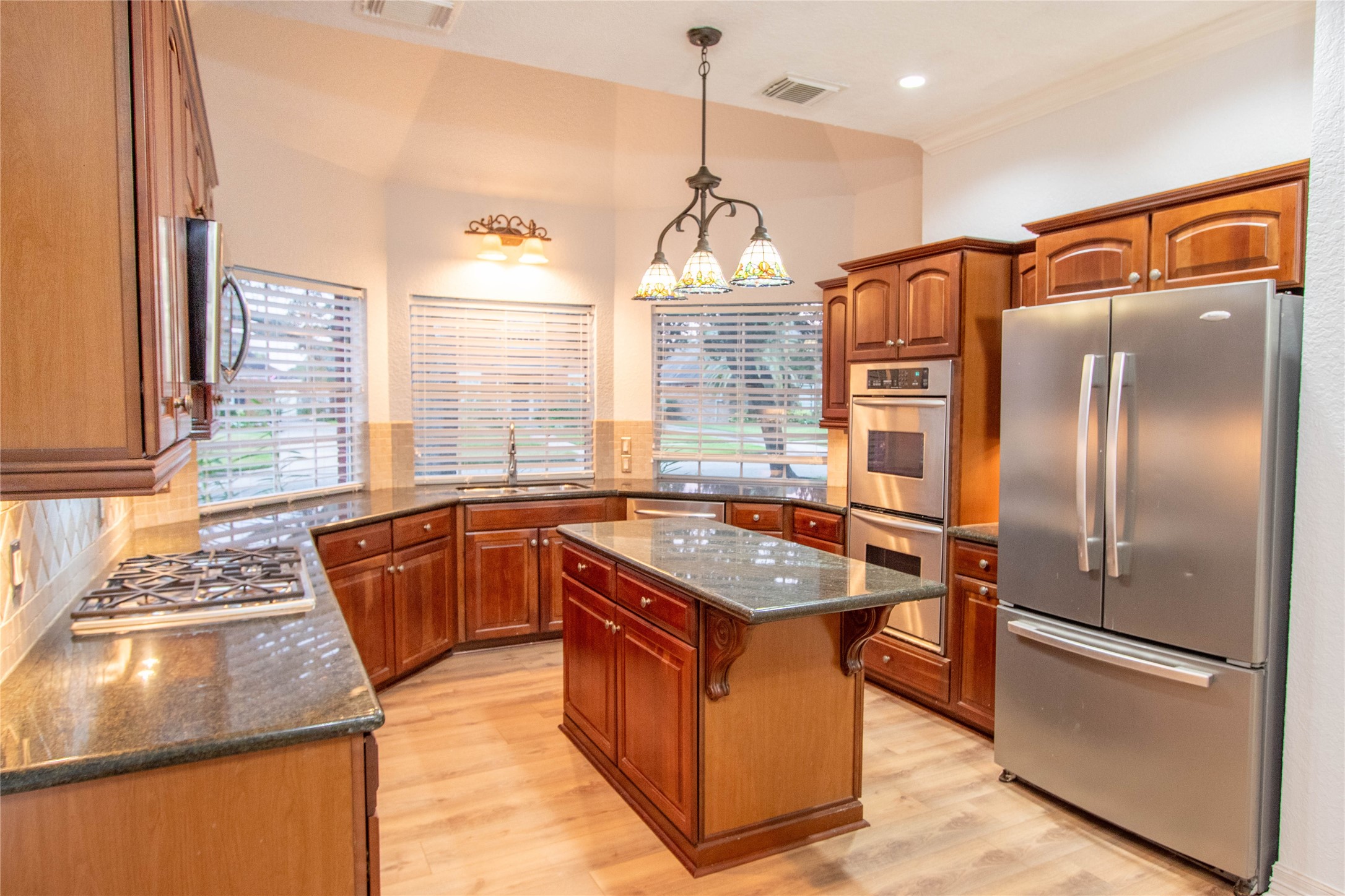 The kitchen with mohagamy wood cabinets has plenty of counter space and three bay windows that overlook at the front yard.