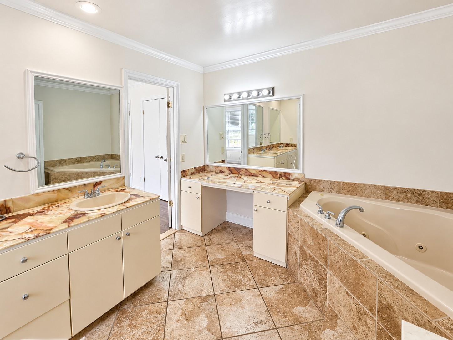 Primary en suite with double sinks, vanity area with seating, large soaking tub, and separate walk-in shower