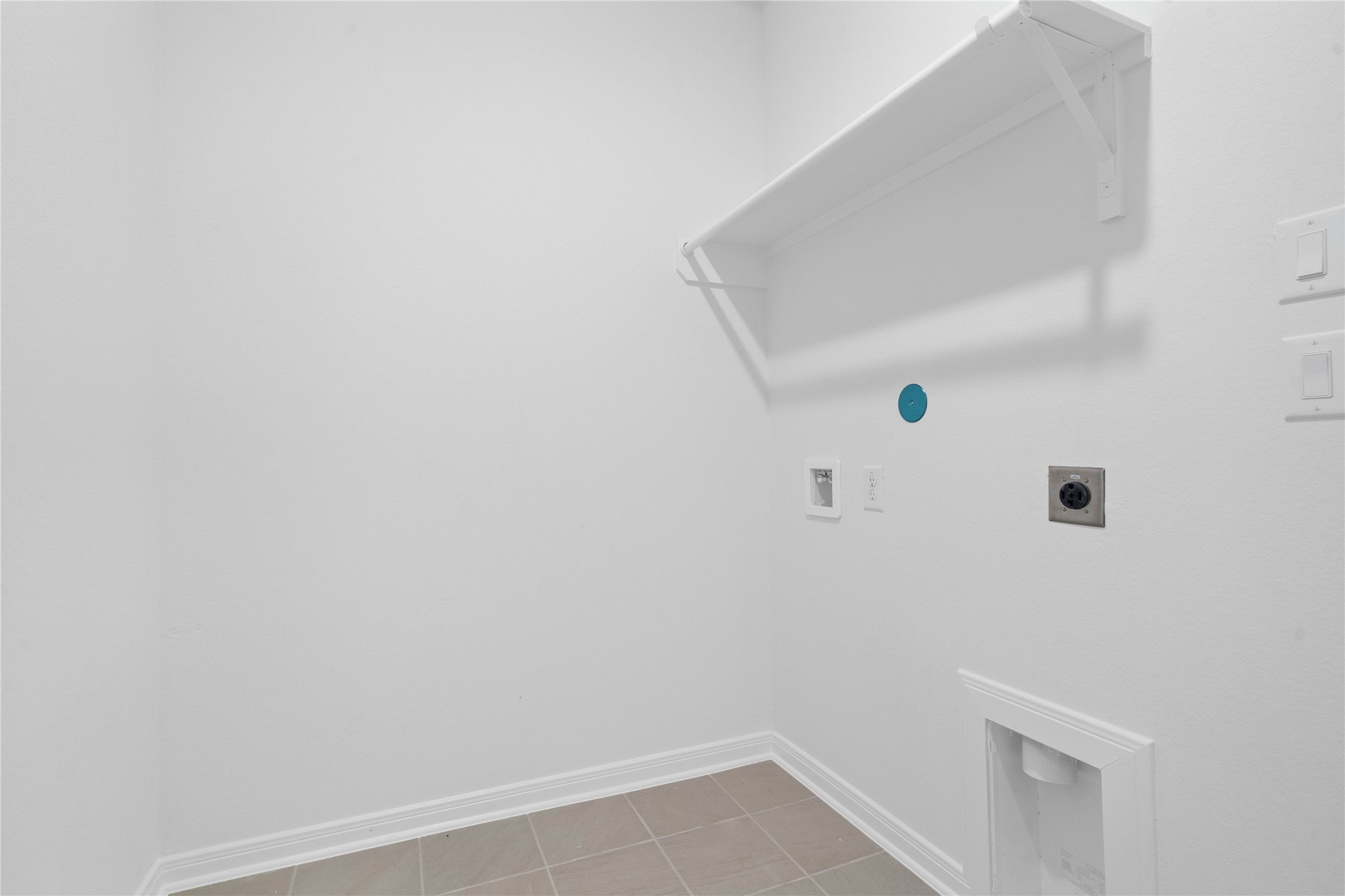 The laundry room features durable Dune colored tile flooring and a functional layout designed to make everyday household tasks more convenient.