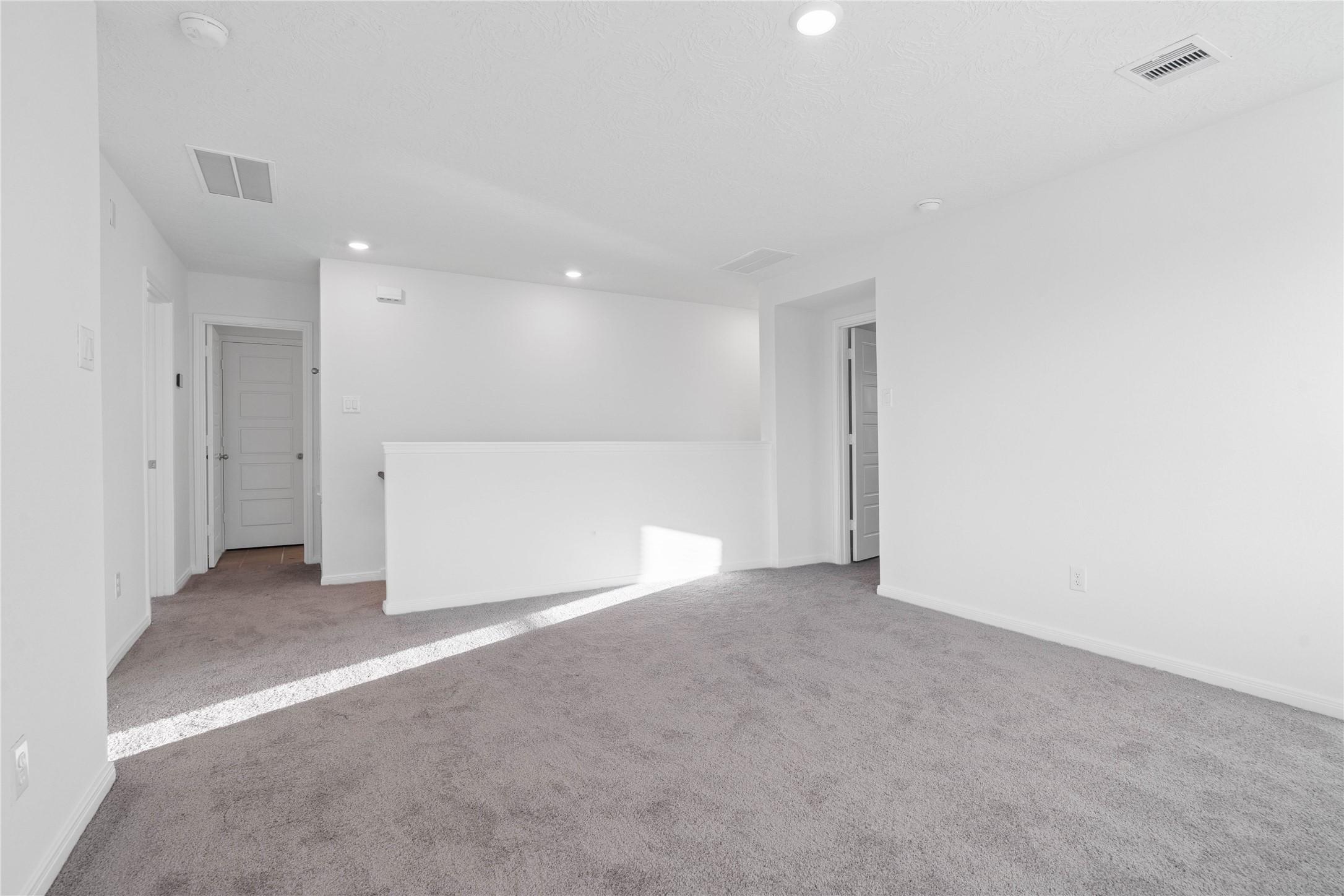 The upstairs layout connects the additional bedrooms, bathrooms, and loft, creating a functional space with room for everyone. Soft gray carpeting and crisp neutral finishes carry throughout the second floor for a clean, cohesive look.