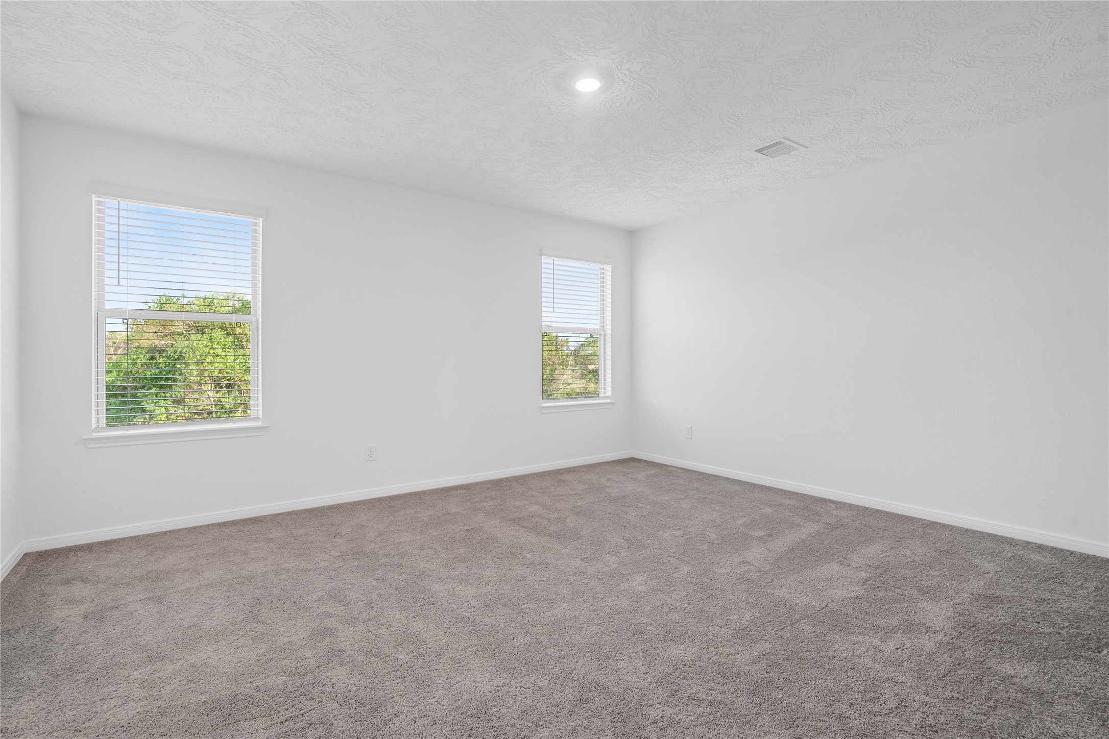 Enjoy a comfortable primary bedroom with plush gray carpeting and bright, neutral finishes that create an inviting atmosphere. With plenty of room to arrange your furniture and make it your own, this space is ready to feel like home.