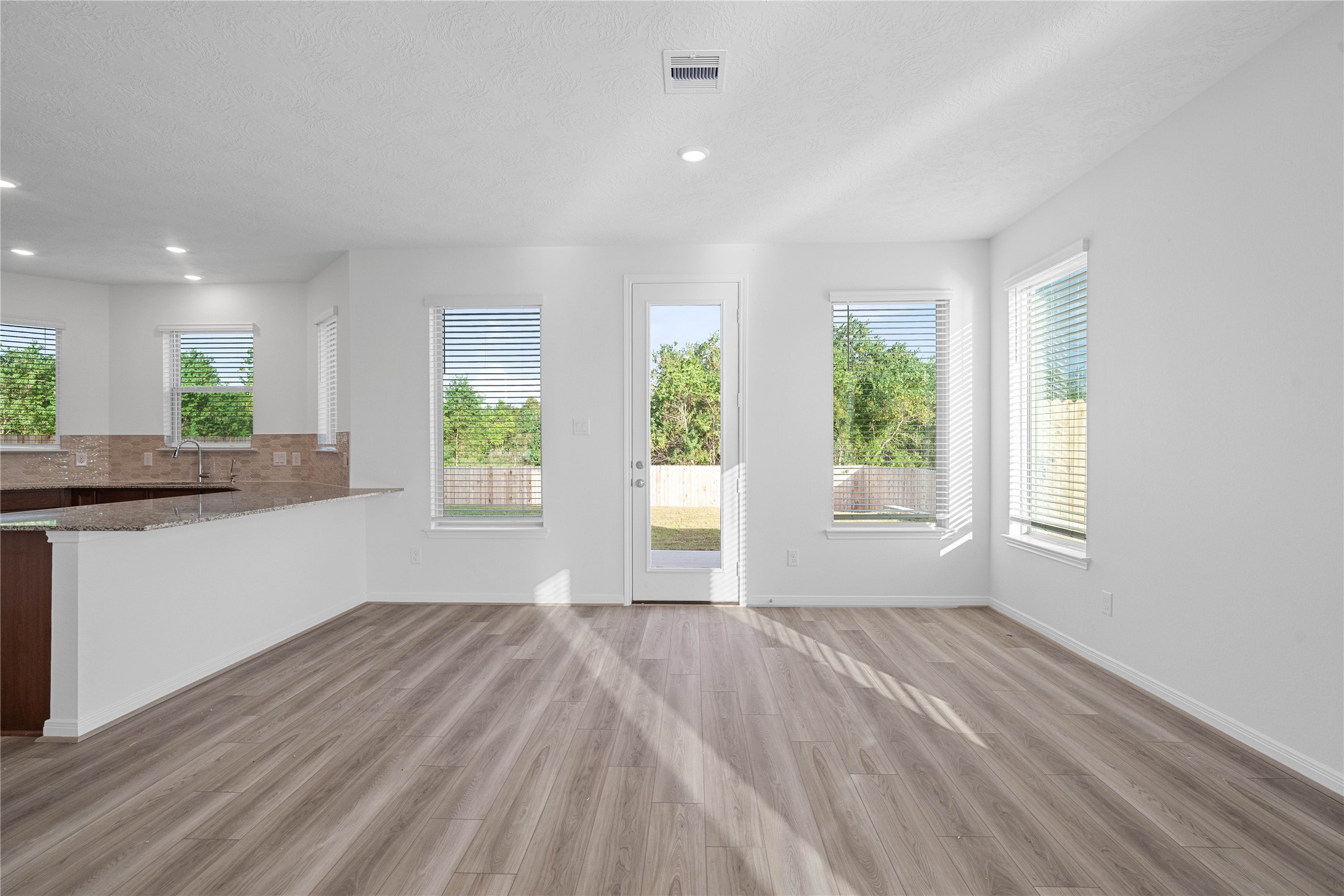 The dining area sits just off the kitchen and living room, creating an open and connected space for shared meals and gatherings. Natural light and warm wood look flooring add to its welcoming feel.