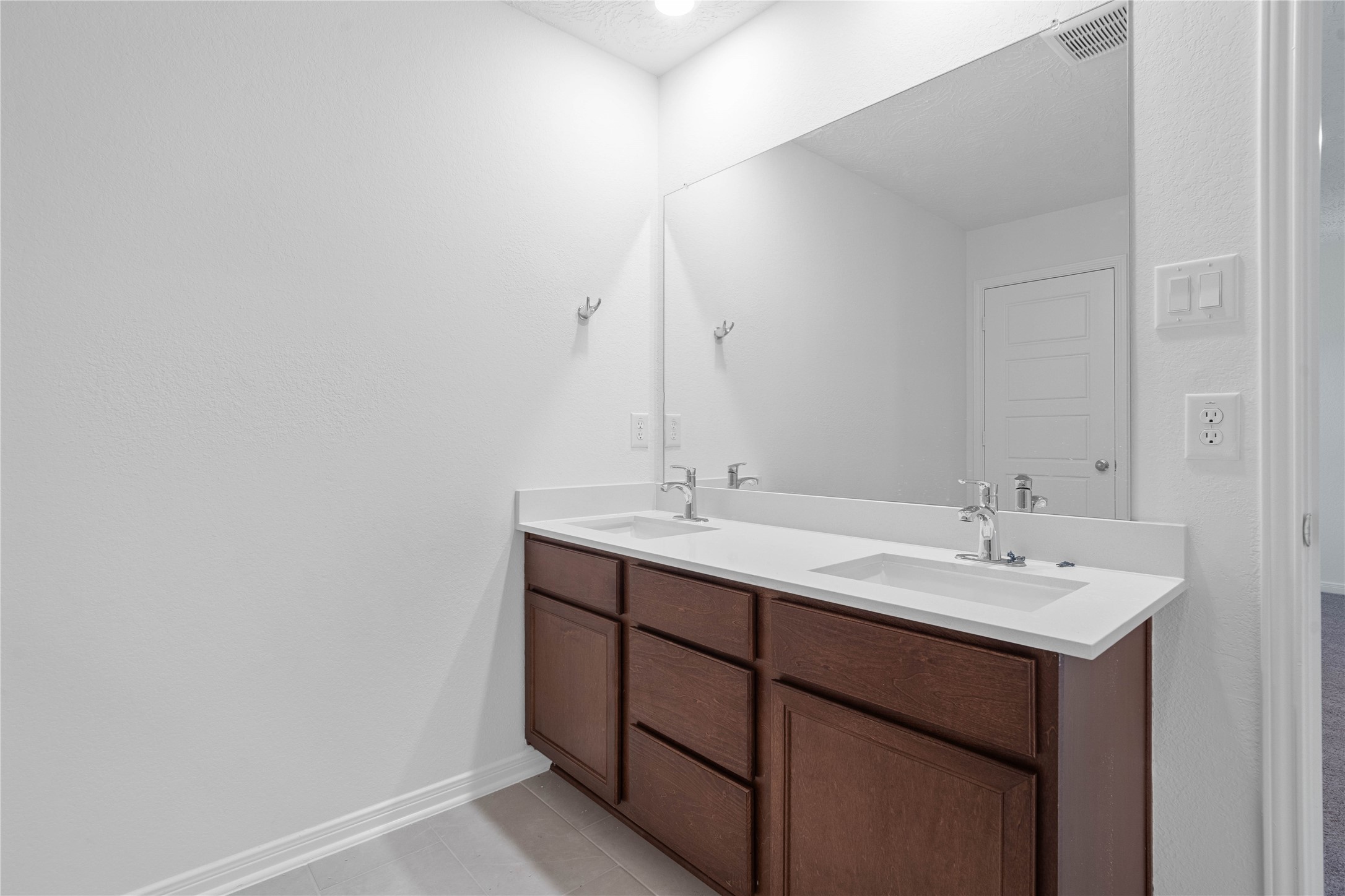The primary bathroom features a dual sink vanity, offering added convenience for busy mornings and everyday routines. A clean, neutral palette and Heirloom White tile surround create a fresh, timeless look.