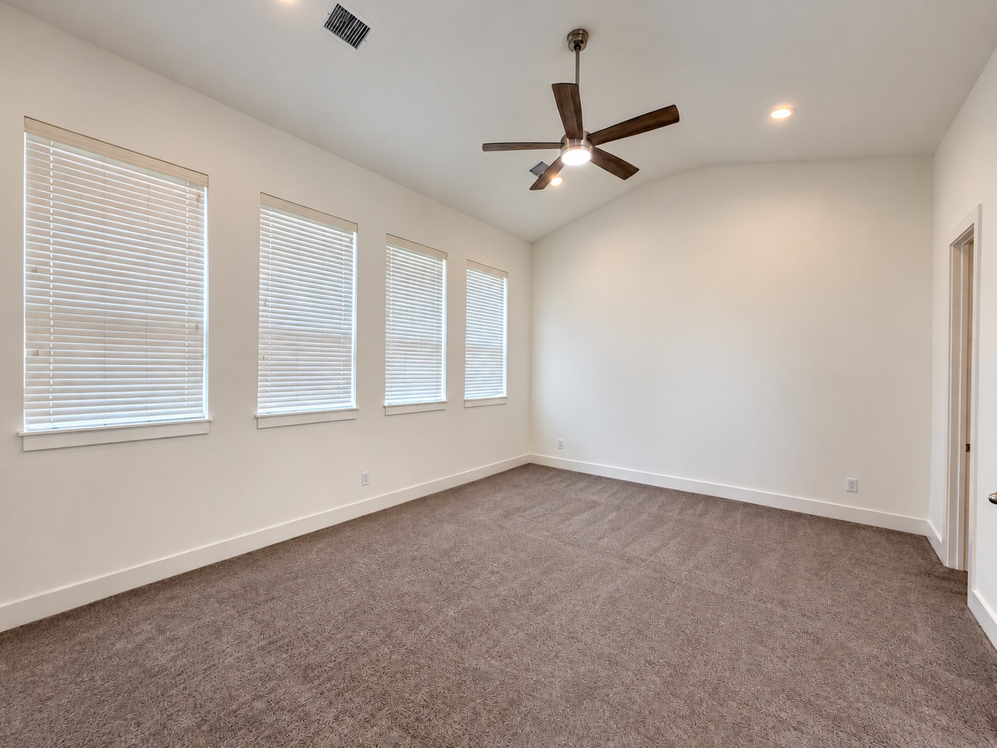 Third-floor bedroom with high ceilings, abundant windows, and soft carpeting.