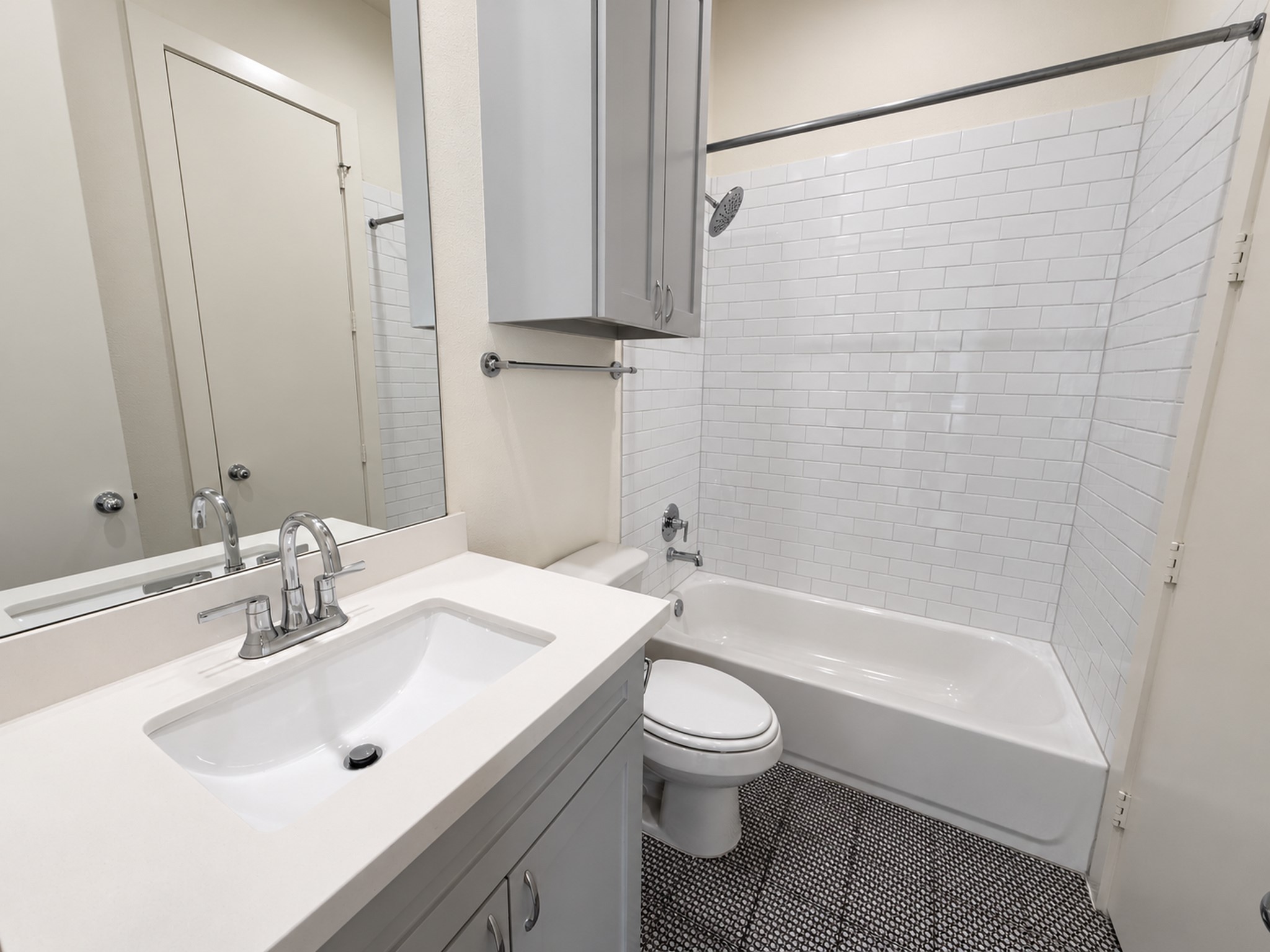 Second-floor bathroom featuring a sleek vanity, modern fixtures, and a subway-tiled tub and shower combination.