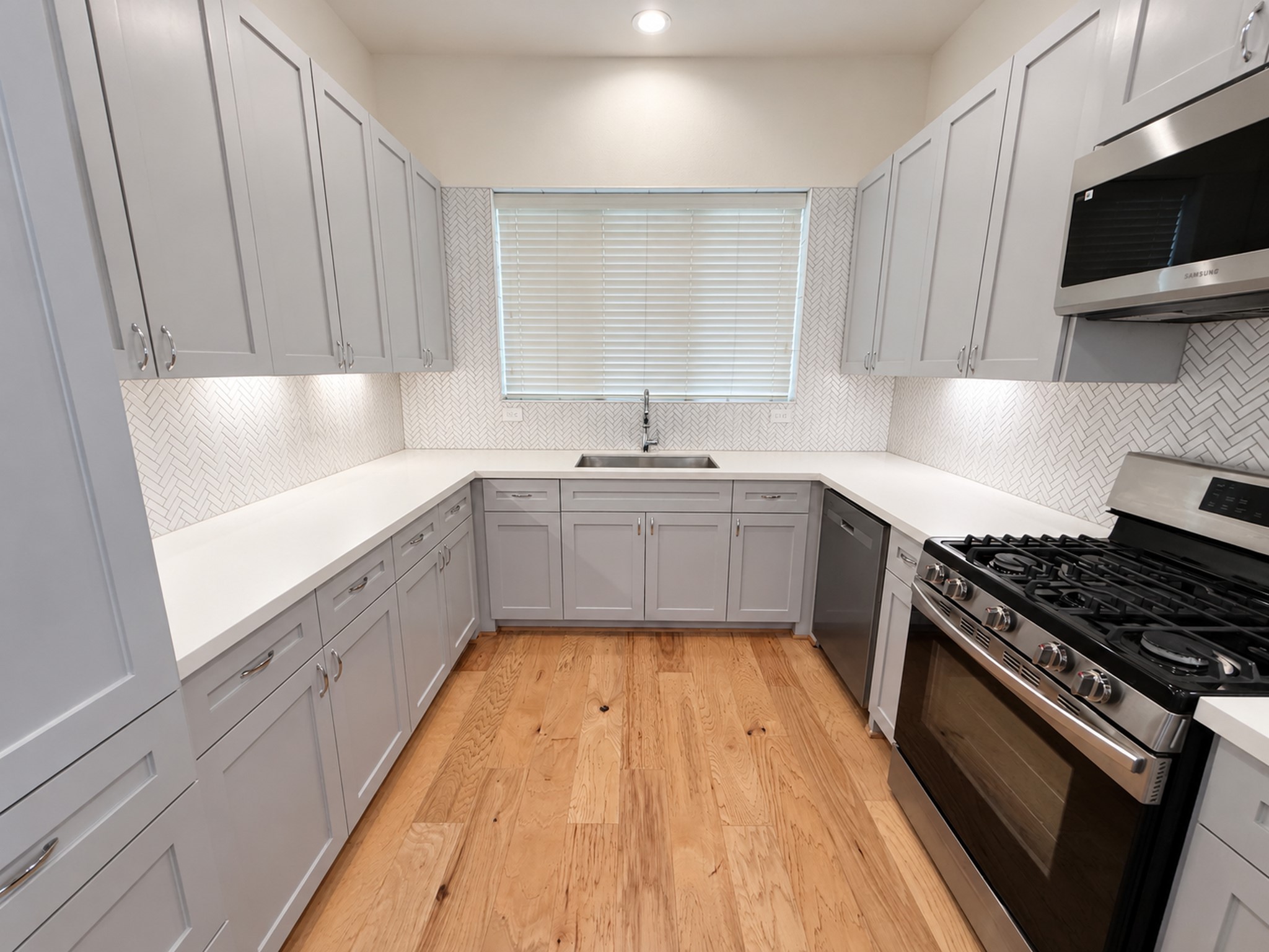 Modern kitchen with beautiful countertops, stainless steel appliances, ample cabinetry, and a stylish tile backsplash.